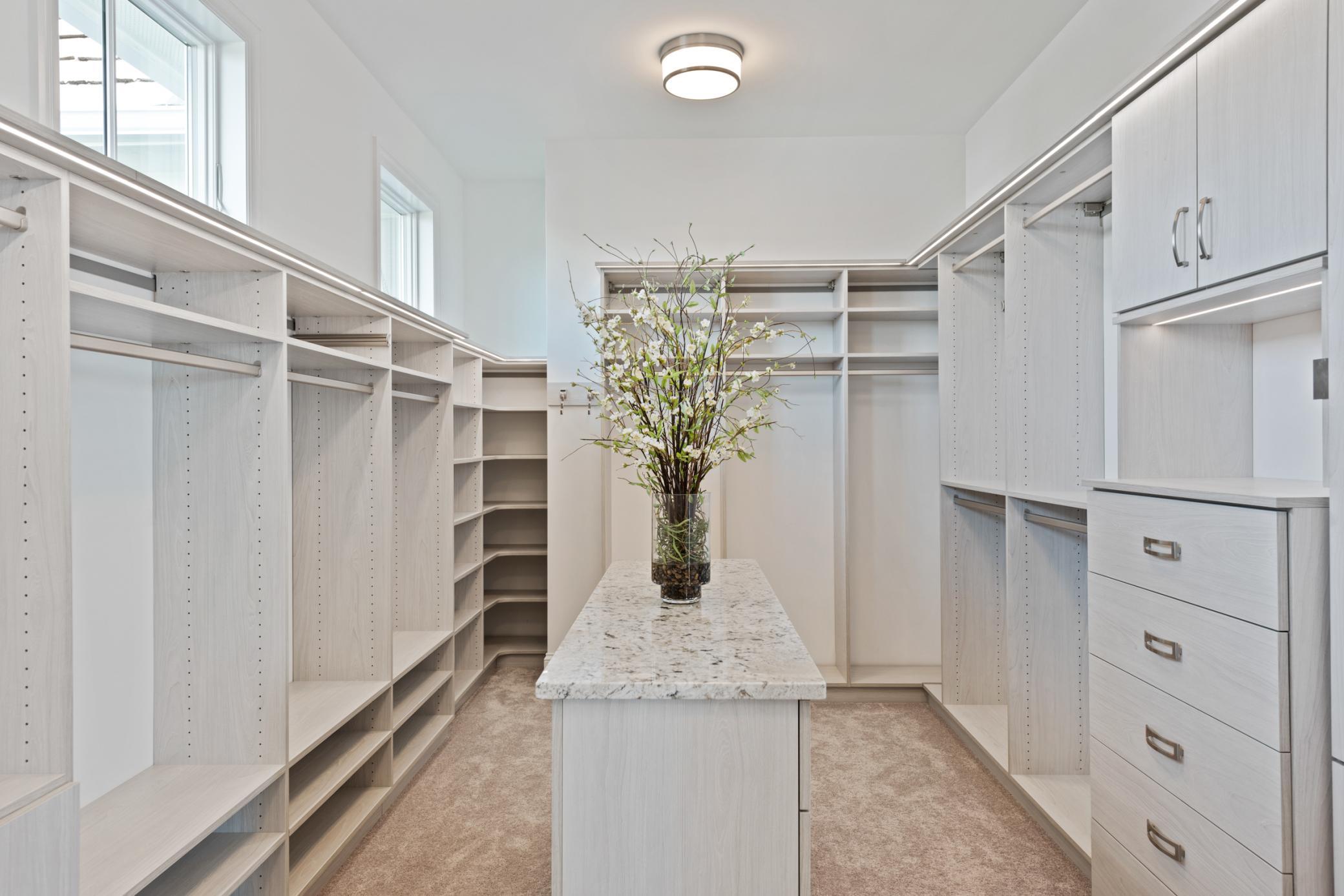 Spacious primary walk-in closet with custom built-ins, center island, and thoughtfully designed storage for effortless organization. Boutique-style walk-in closet featuring ample shelving, hanging space, and a center island—perfect for showcasing a