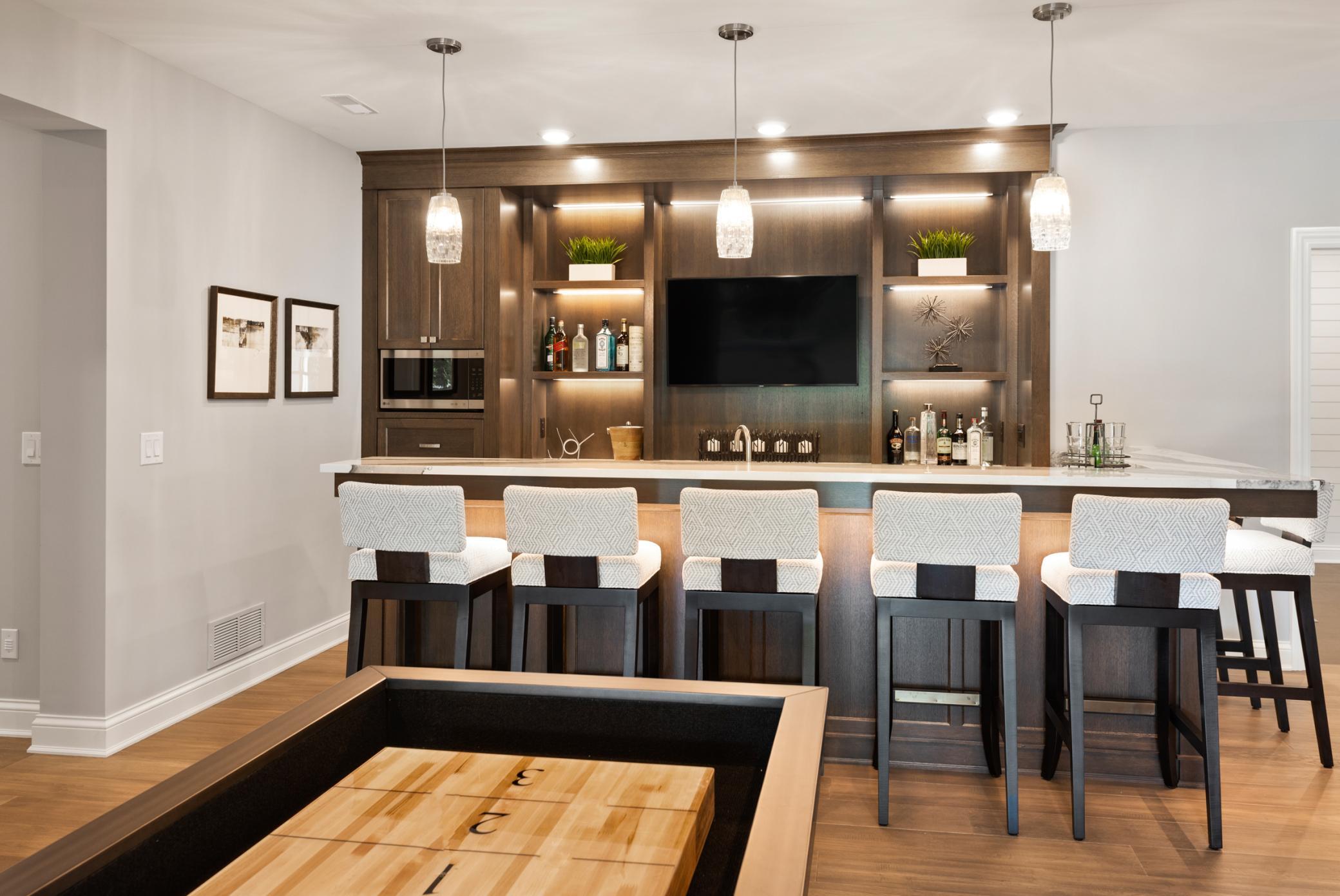 Lower level wet bar with seating, designer lighting, and shelving to display your favorite bar items