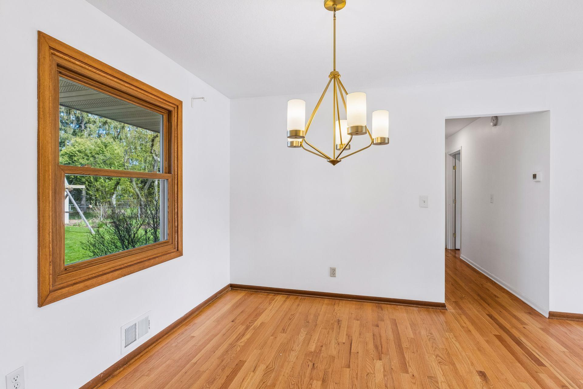 The dining room is open to the living room, kitchen, and hallway leading to bedrooms.