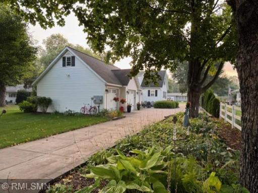 Rear view showing long concrete driveway, large 3-car garage, and large hosta garden.