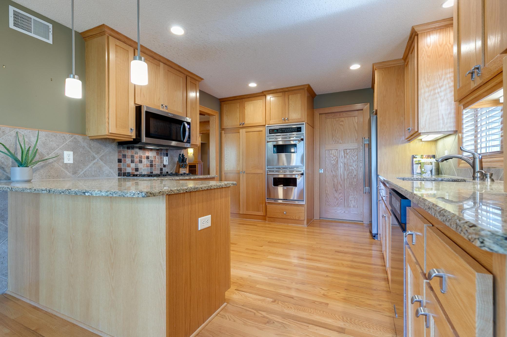 This kitchen features granite countertops, complemented by stainless steel appliances and a ceramic backsplash for a warm, polished look.