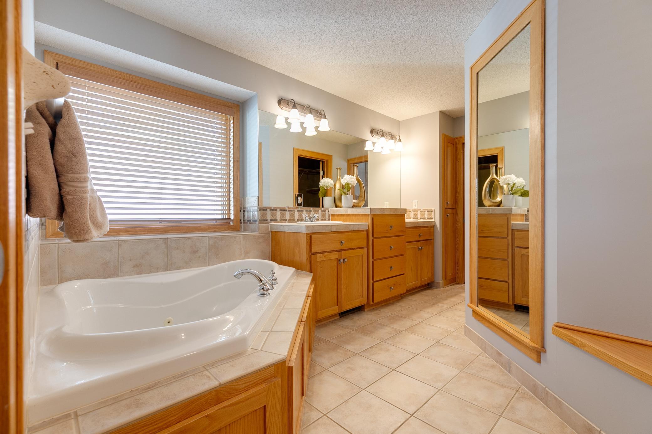 The spacious private bathroom features a walk-in shower, a separate jetted tub, walk-in closet and dual sinks.