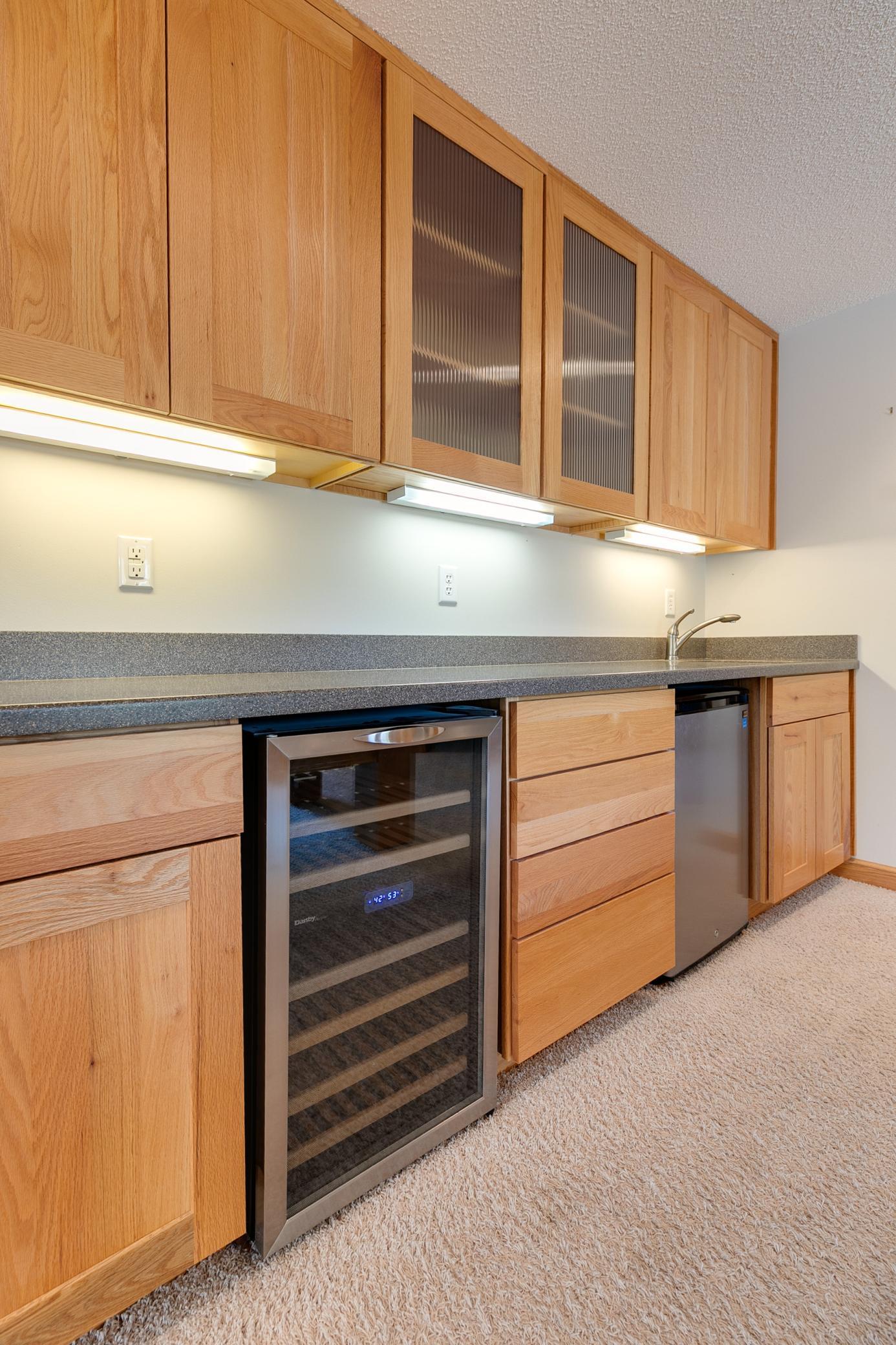 The wet bar is equipped with a wine cooler and a refrigerator, making it easy to grab a refreshing drink.