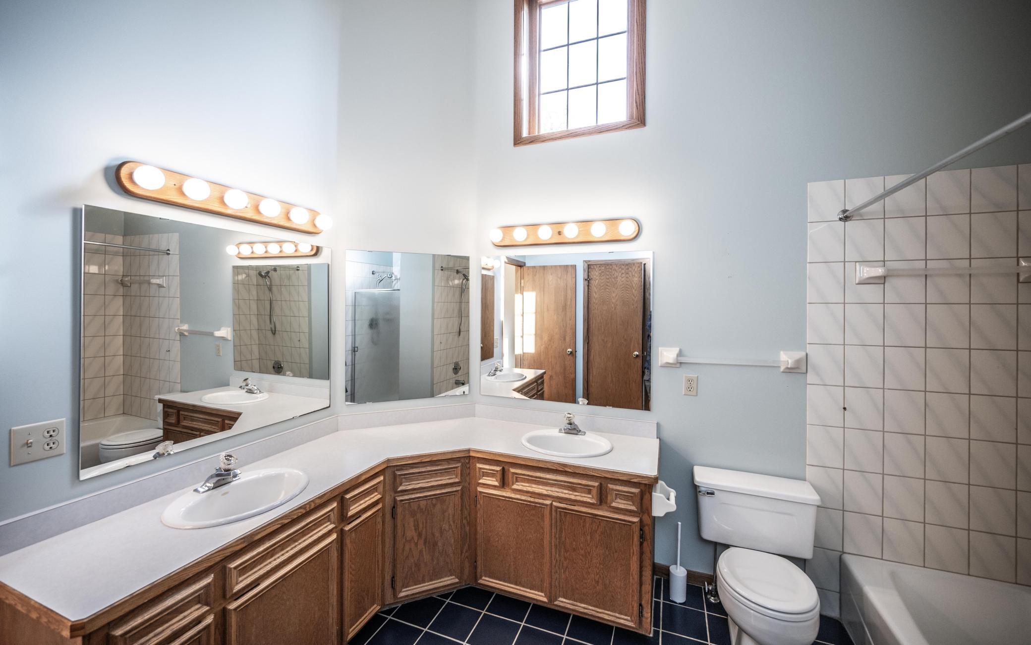 Full bath on the upper level features double sinks, tile floor, tile tub surround, vaulted ceiling and a separate shower with tile surround