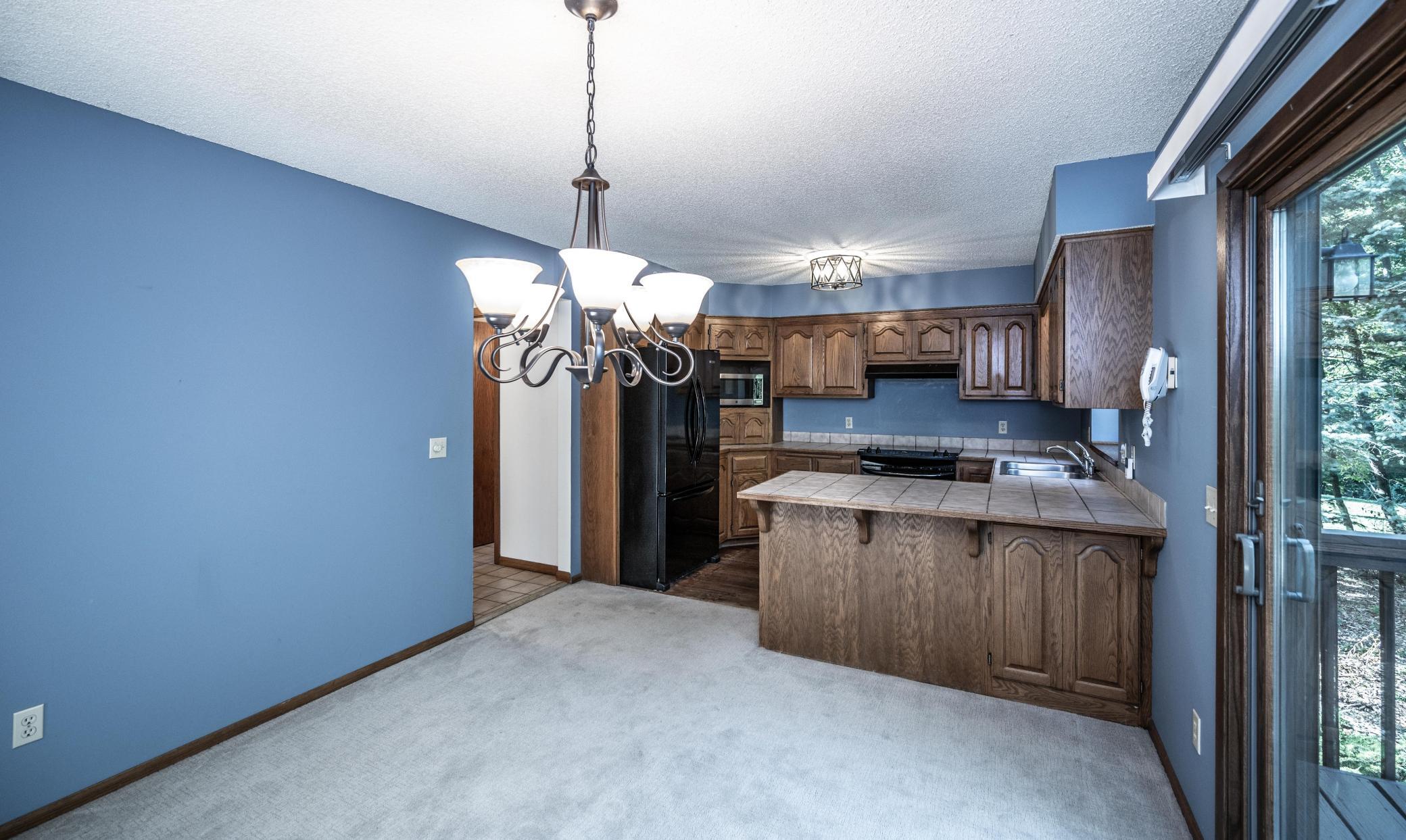 Informal dining area has newer carpet and a sliding glass door to the deck