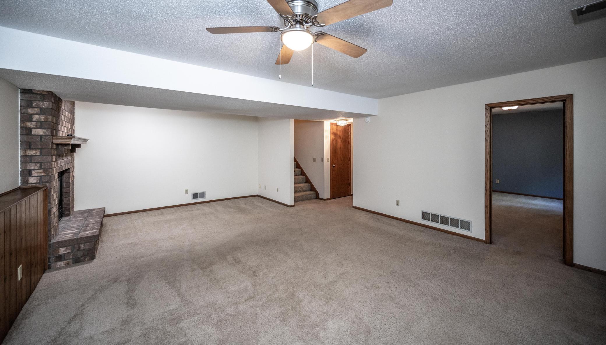 Large lower level family room with gas fireplace (with floor to ceiling brick surround) and ceiling fan