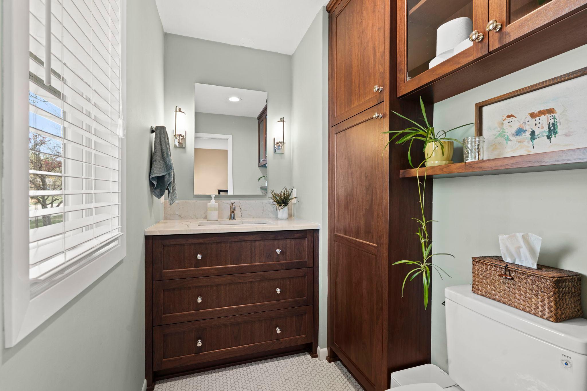 Primary 1/2 bathroom with great linen storage, floating shelves and tiled floors. Remodeled in 2023!