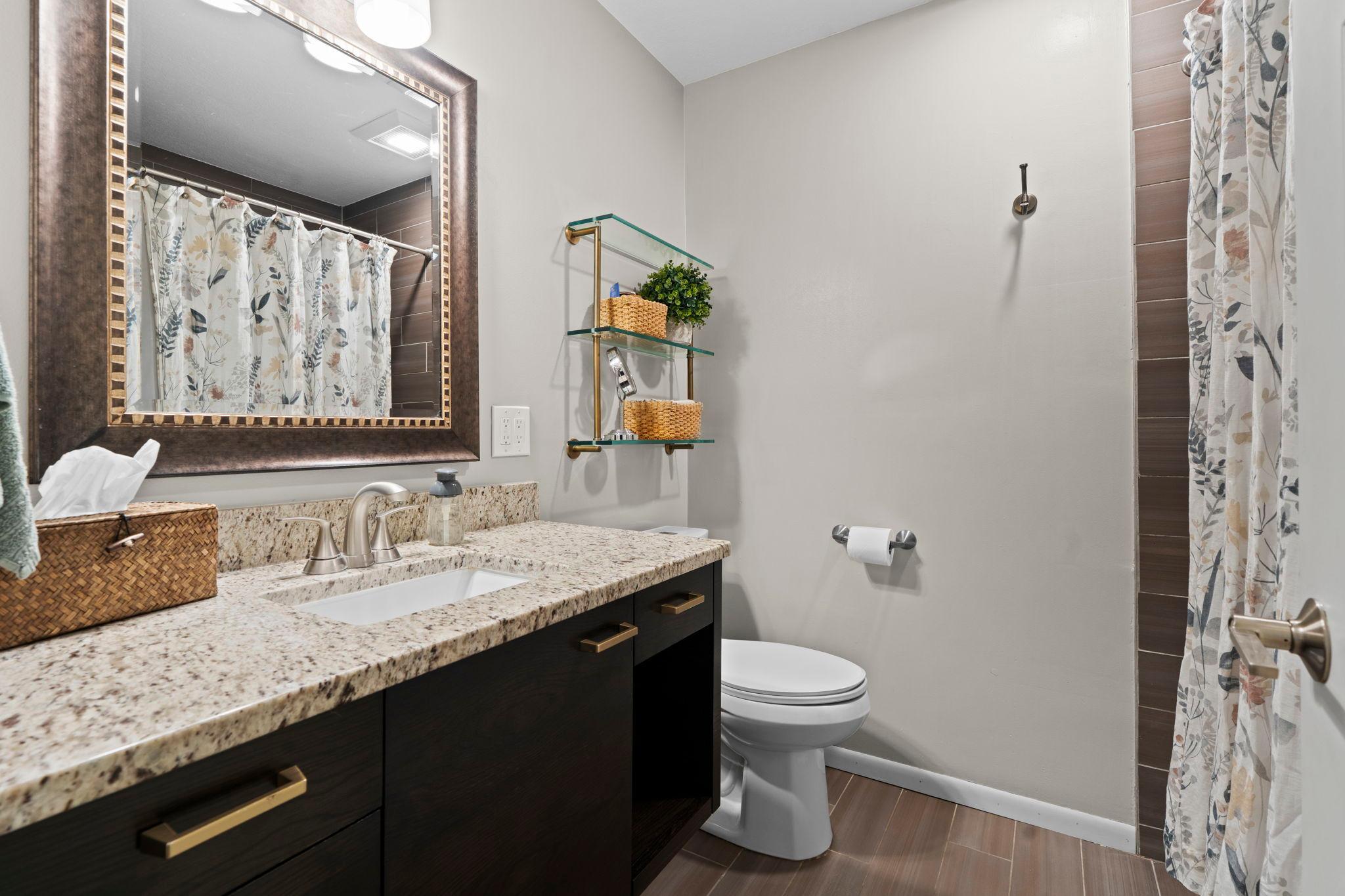 Full, main level bathroom with modern vanity, Granite countertops and tiled floors.