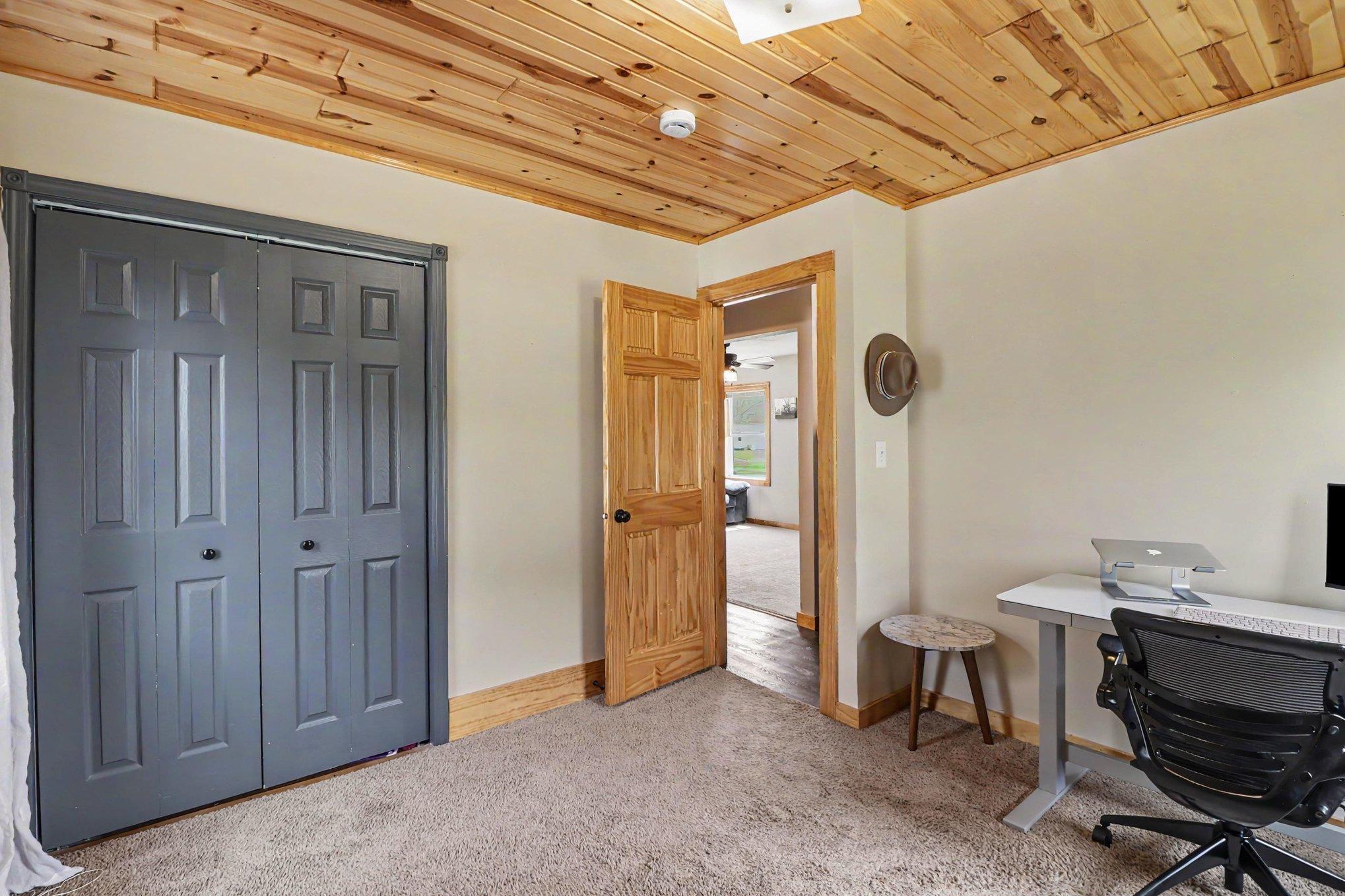 Second main floor bedroom with pine plank walls, natural light, and 6-panel solid door