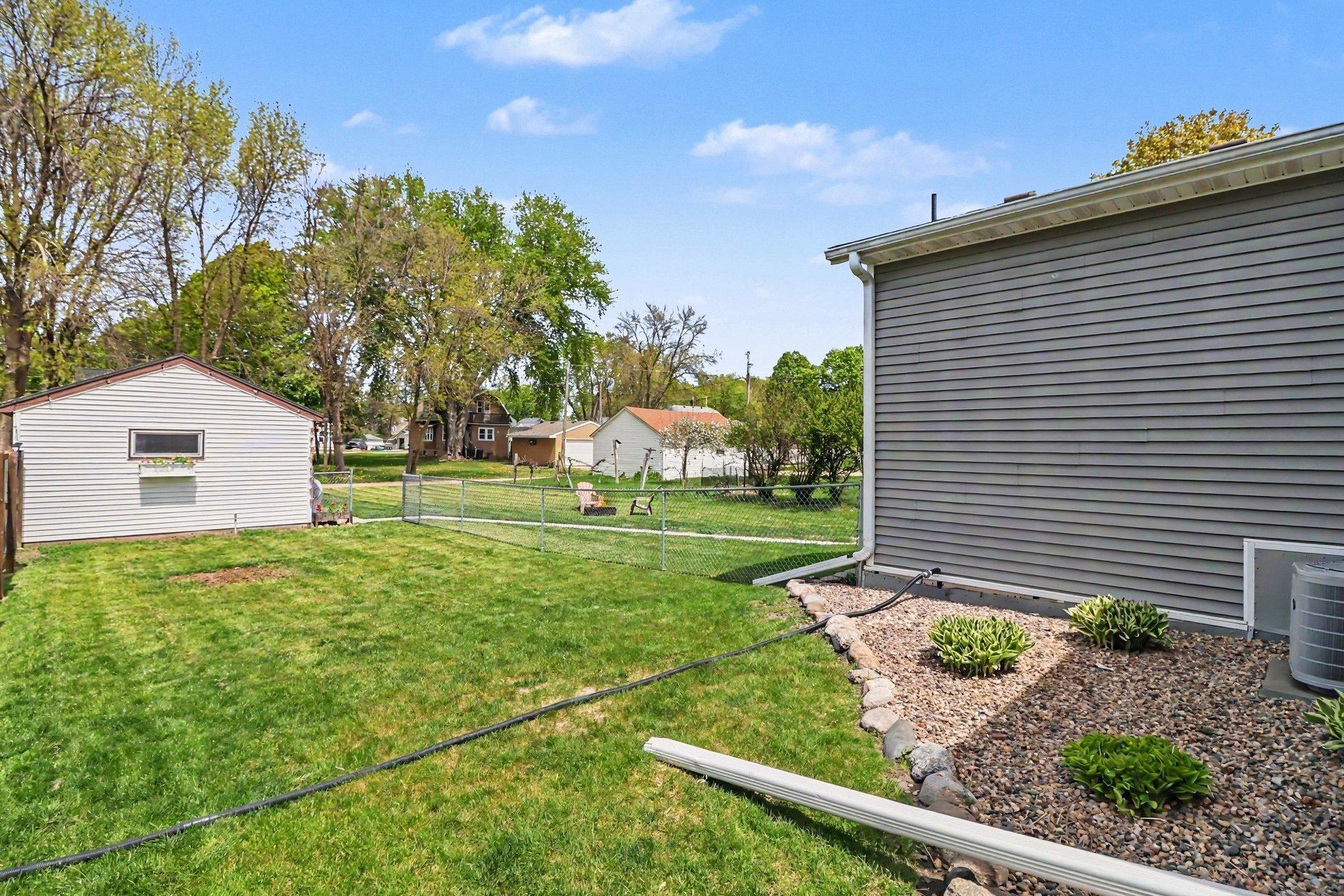 Rear yard view showing mature trees, open lot, and neighboring green space — steps to Memorial Park