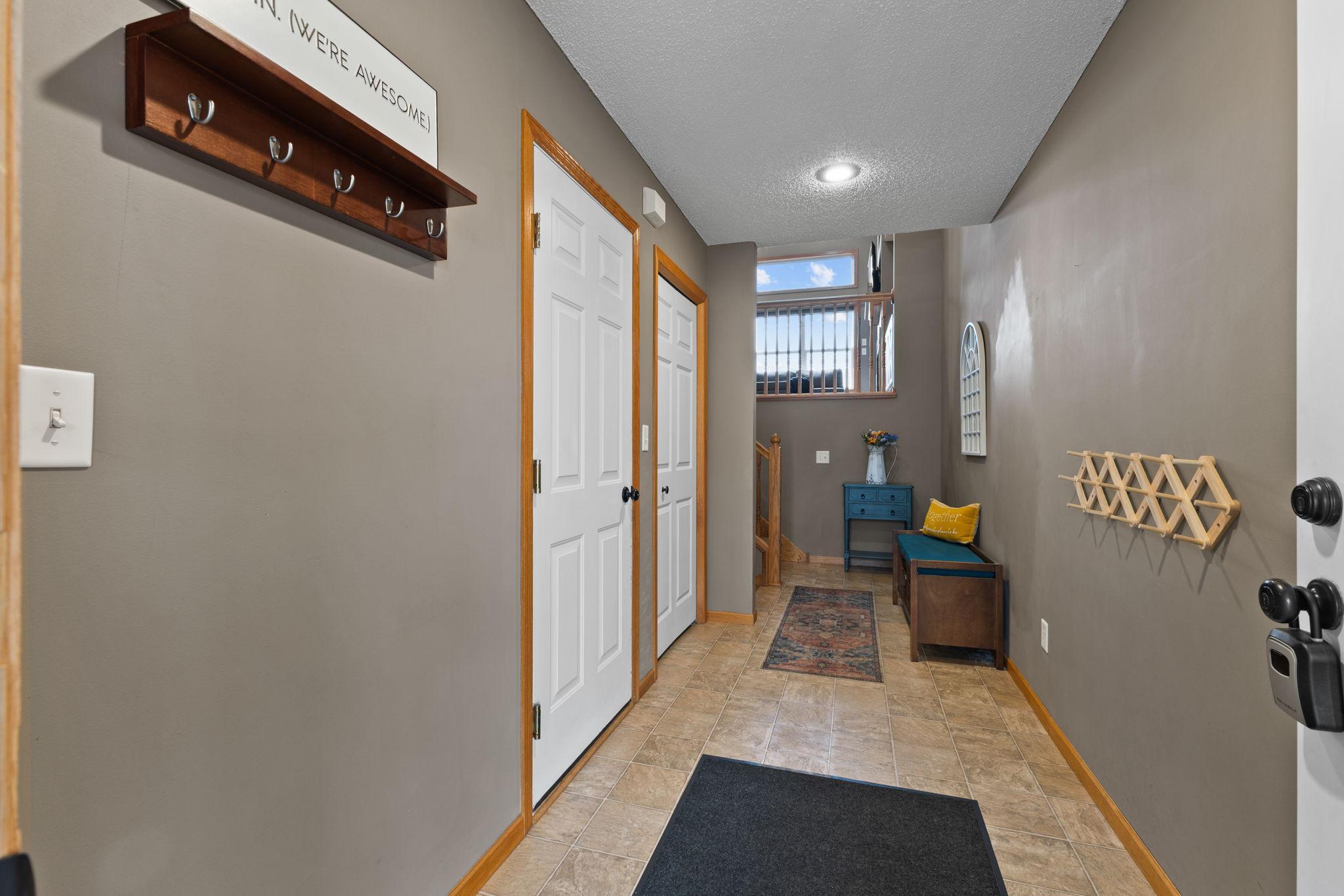 A welcoming large foyer. The first door to the left is to the garage and the second set of doors is a coat/storage. closet. straight ahead to the left is a set of stairs to go up and another set of stairs to go to the finished lower level.