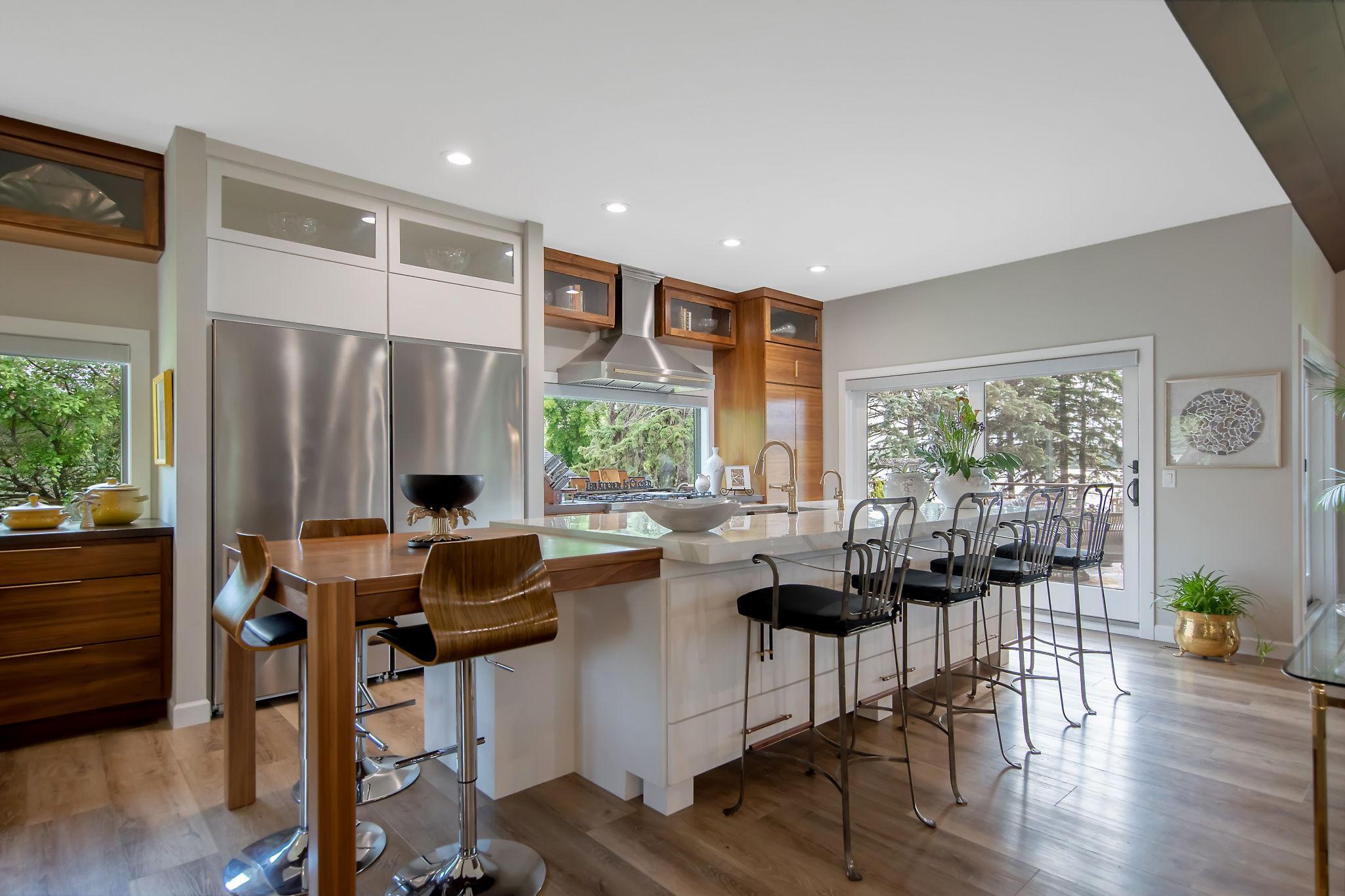 Gourmet kitchen featuring a 10-foot center island, a custom-built walnut breakfast table and 55" workstation sink, perfect for cooking, entertaining, or simply taking in the outdoor scenery and wildlife as you prepare meals.