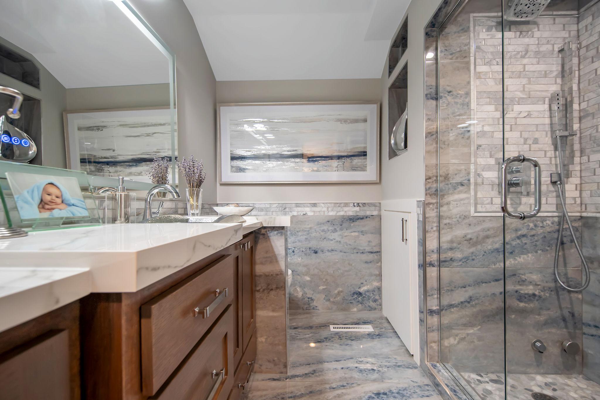 Lower level 3/4 bath with dual custom vanity, steam shower, lighted mirror, heated floors & porcelain tile surround.