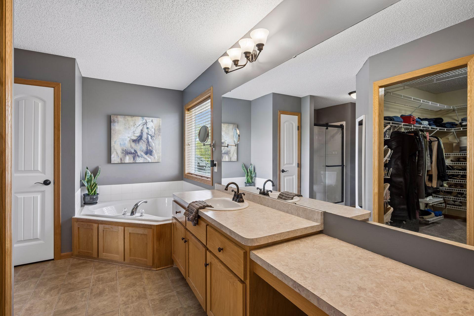 Primary bath features a separate jetted tub and shower, ample counter space, and a large walk-in closet.