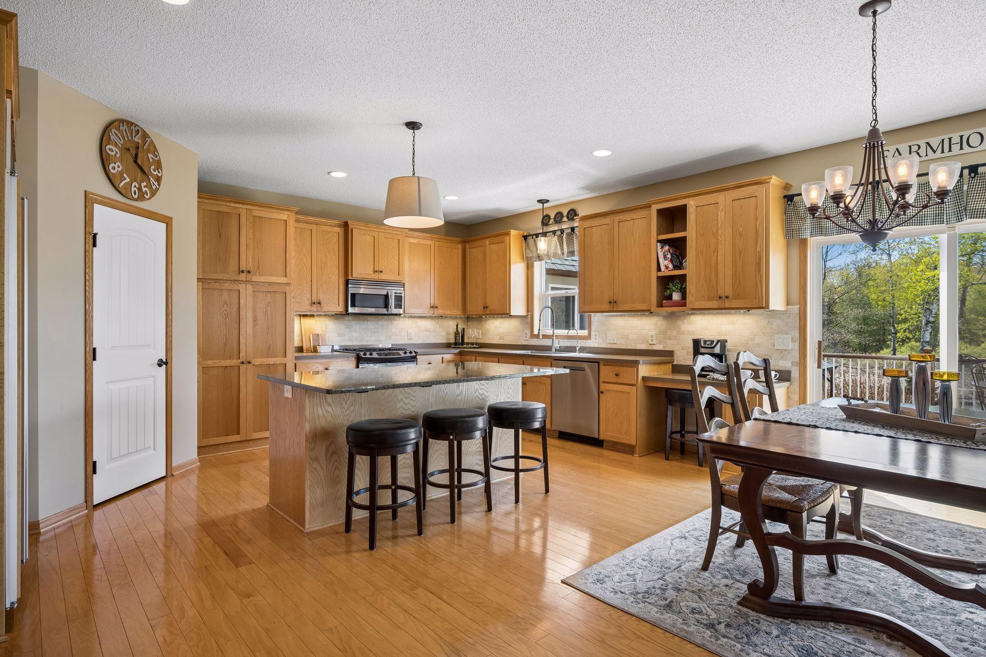 Kitchen features ample cabinetry, large center island, gleaming hardwood floors, corner pantry, tile backsplash, and Sub-Zero refrigerator.