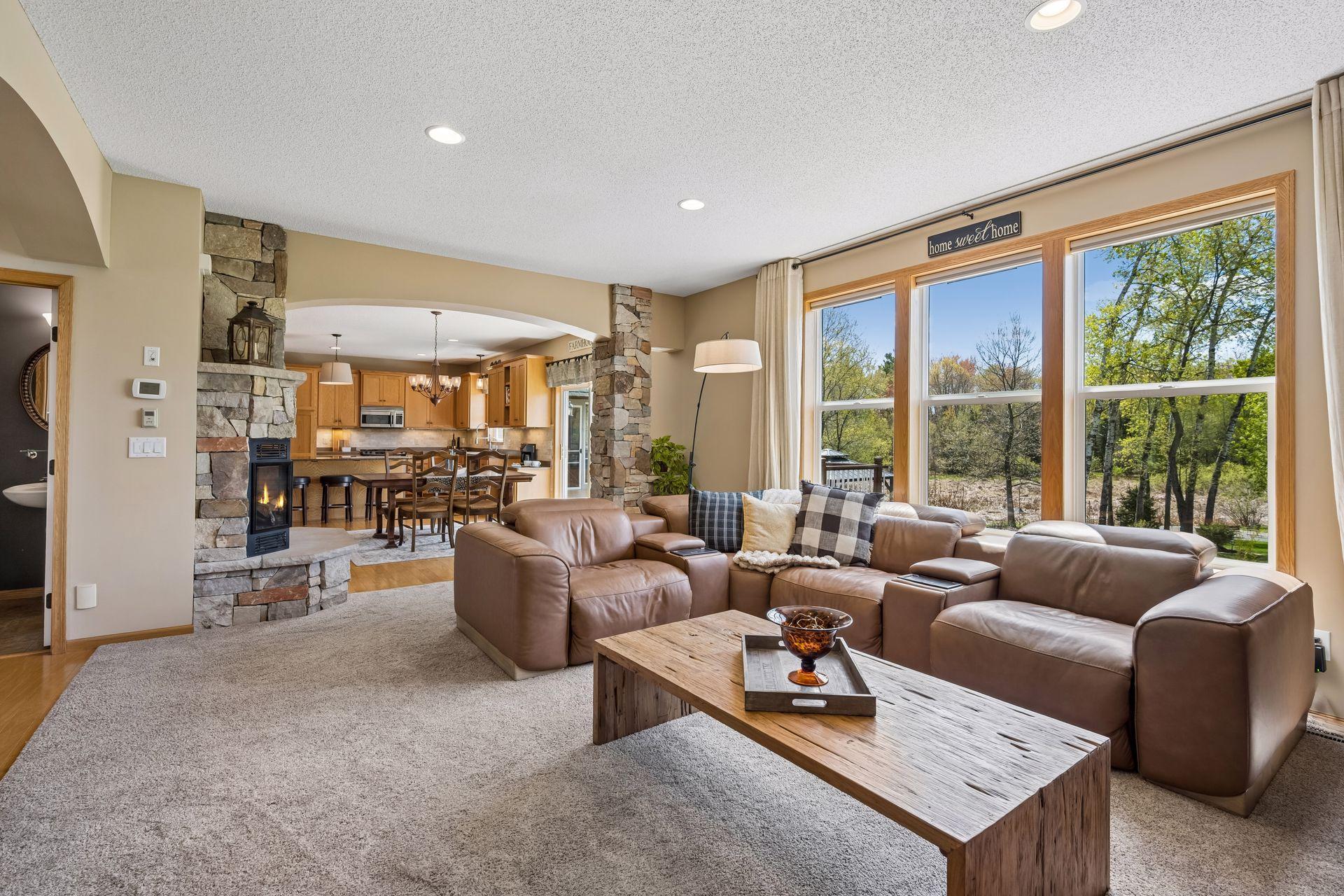 Open and inviting living space with stone fireplace and expansive backyard views.
