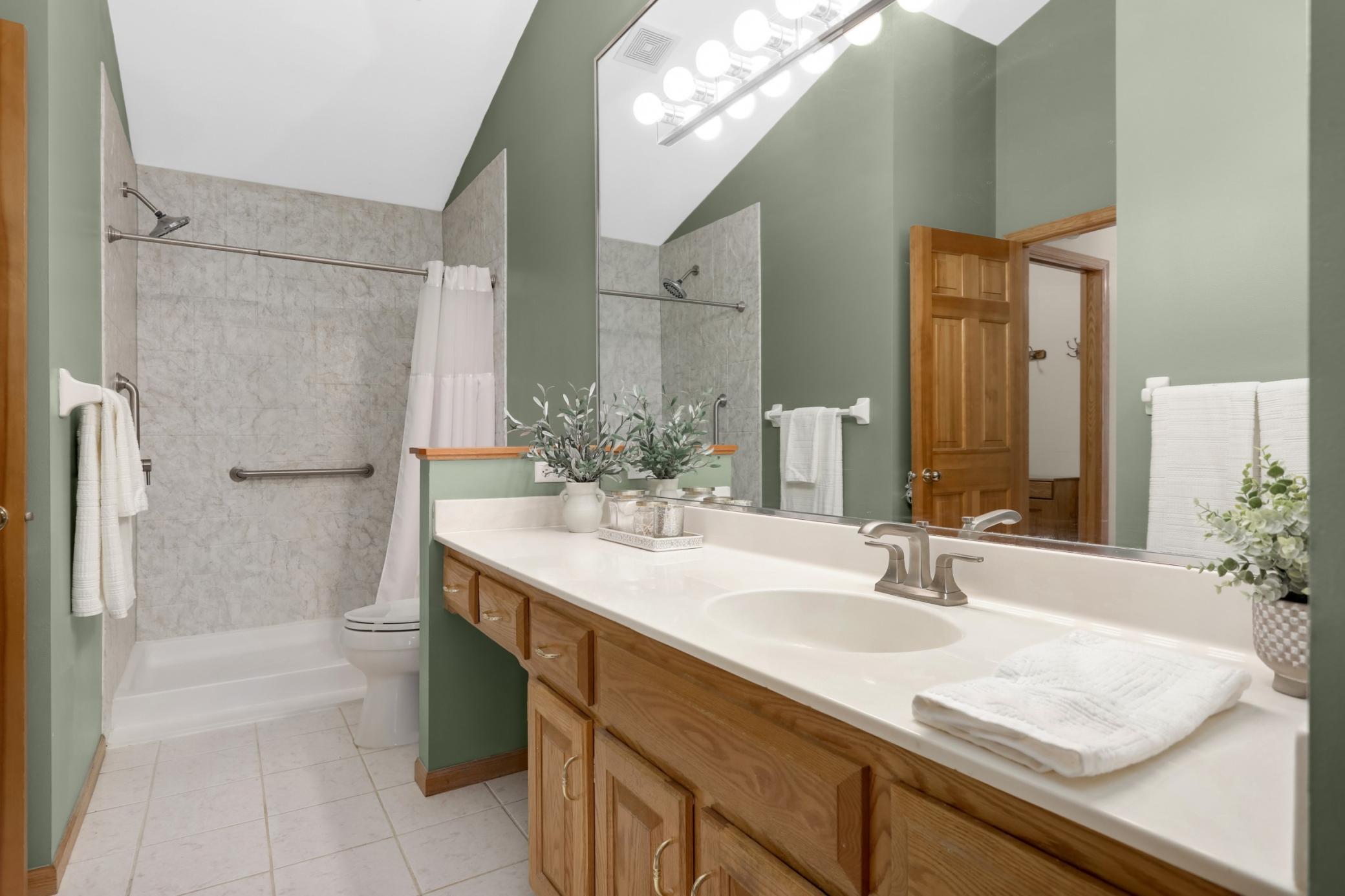 The spacious walk-in shower features safety bars, and the bathroom has an abundance of storage.