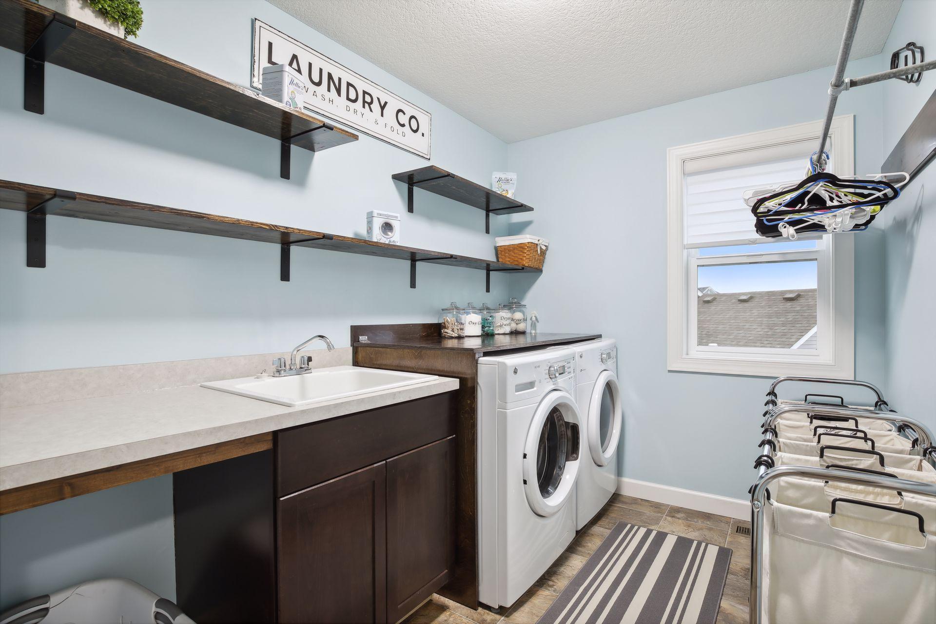 The well-designed and executed upper level laundry has built in shelves, countertop, utility sink and folding and hanging spaces.