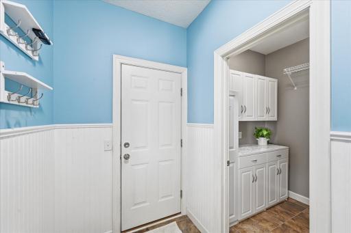The mud room walk-in closet is customized with ample hanging space and cabinets with counter top