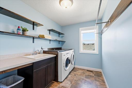 This well designed and executed upper level laundry has folding table, cabinets, open shelves and hanging space.
