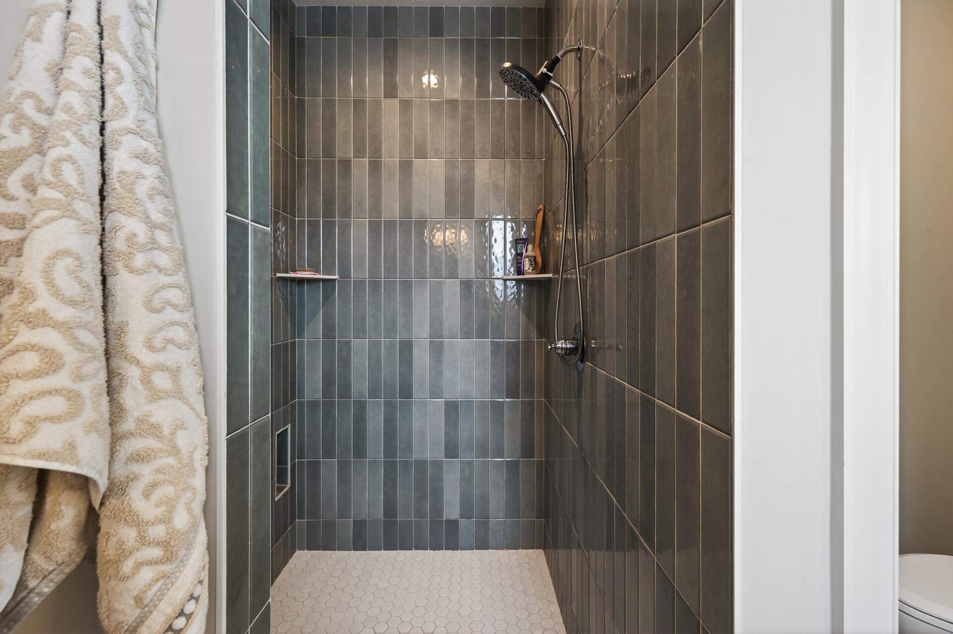 Walk-in primary bathroom shower with glass door and shower wand