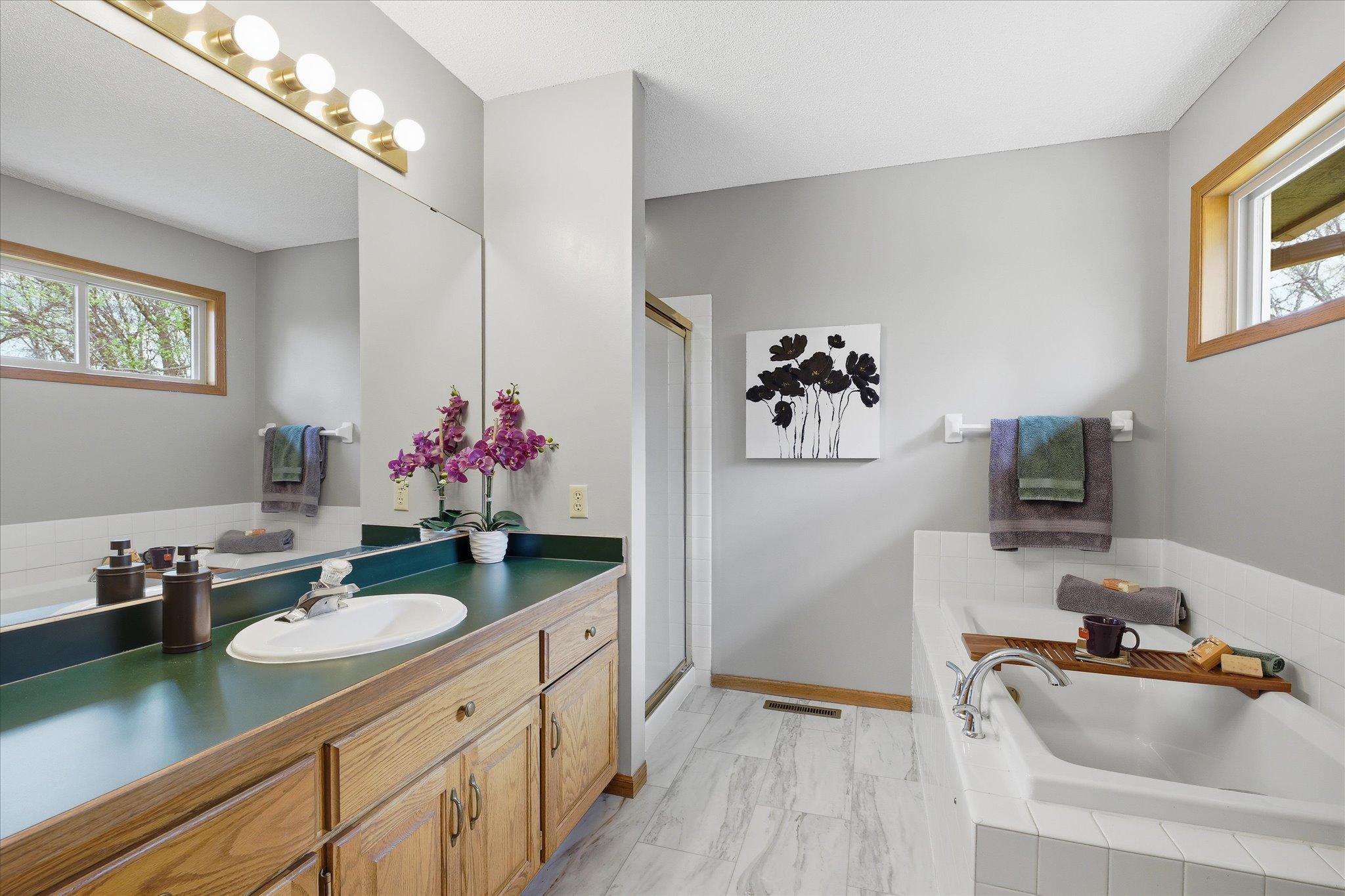 This private primary full bath comes loaded with a jetted tub, a new window, a walk-in shower, new LVT flooring and an extra large oak vanity.