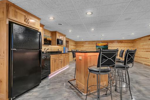 The full wet bar features a refrigerator-freezer, a dishwasher, a slide-out pizza oven, and granite countertop bar.