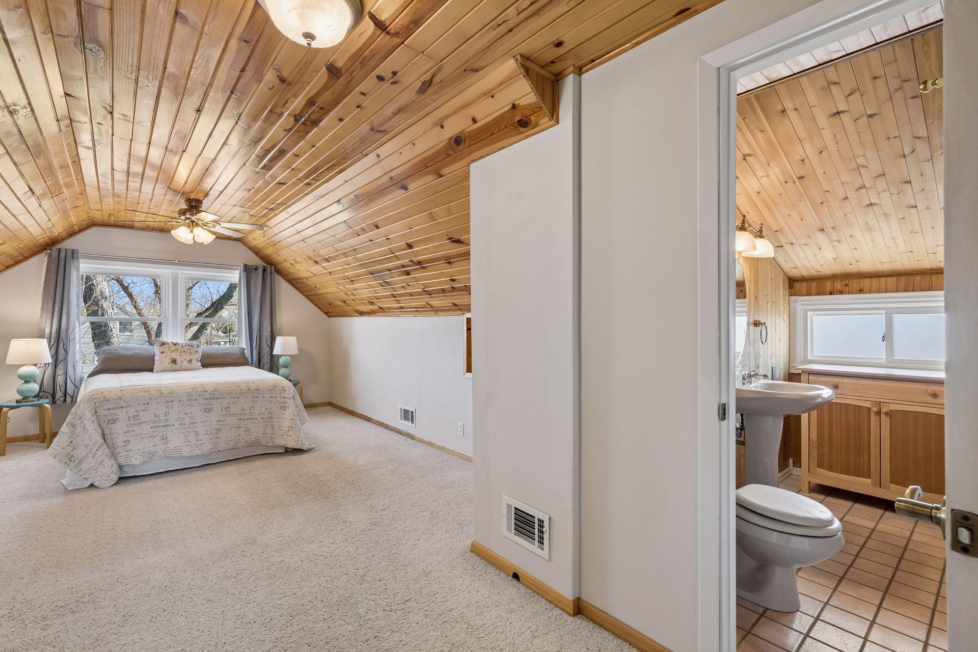 The natural wood-clad ceiling provides a calm and inviting primary bedroom.