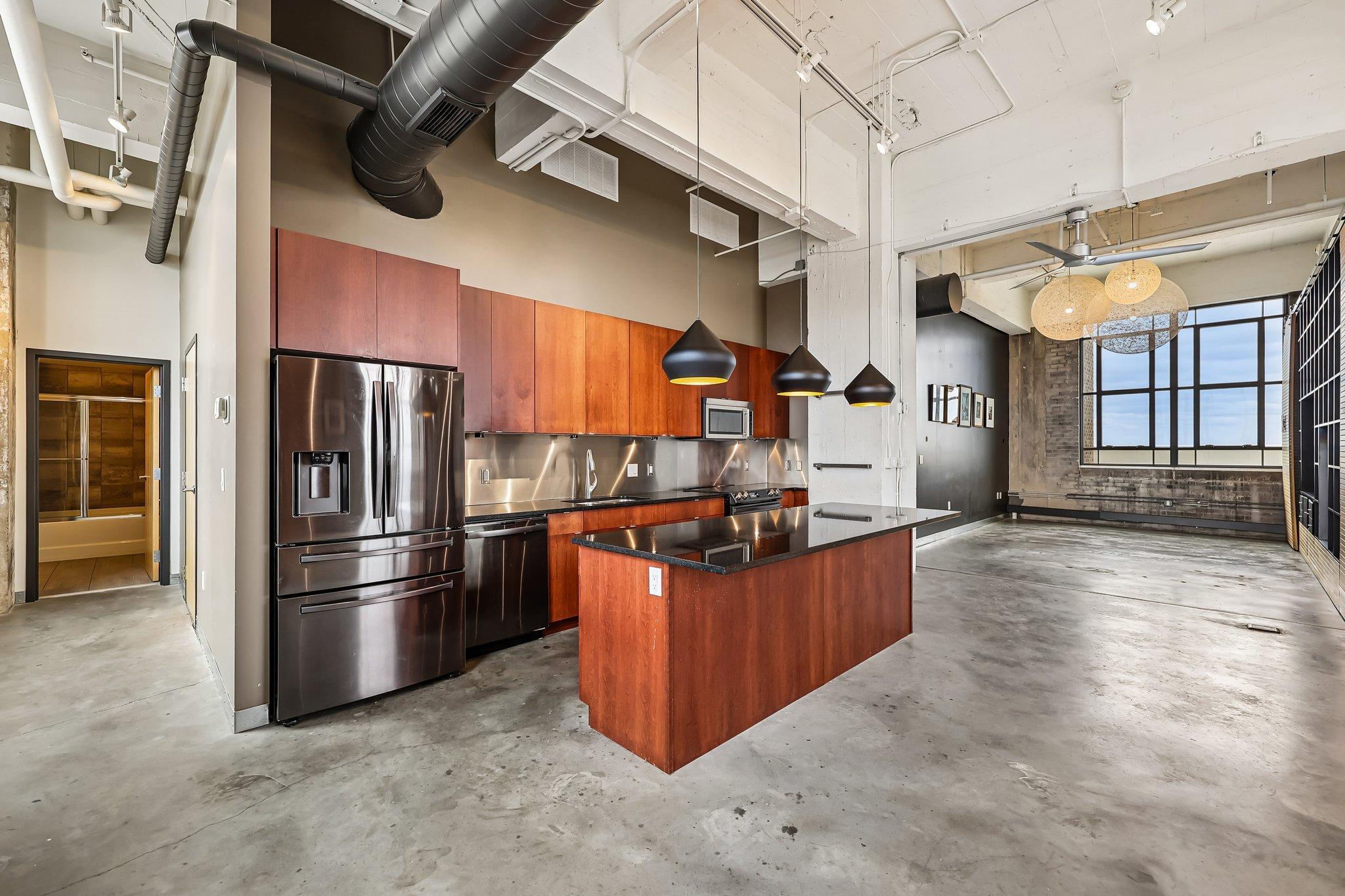 Custom granite-top kitchen, breakfast bar seating, stainless steel appliances and modern light fixtures.