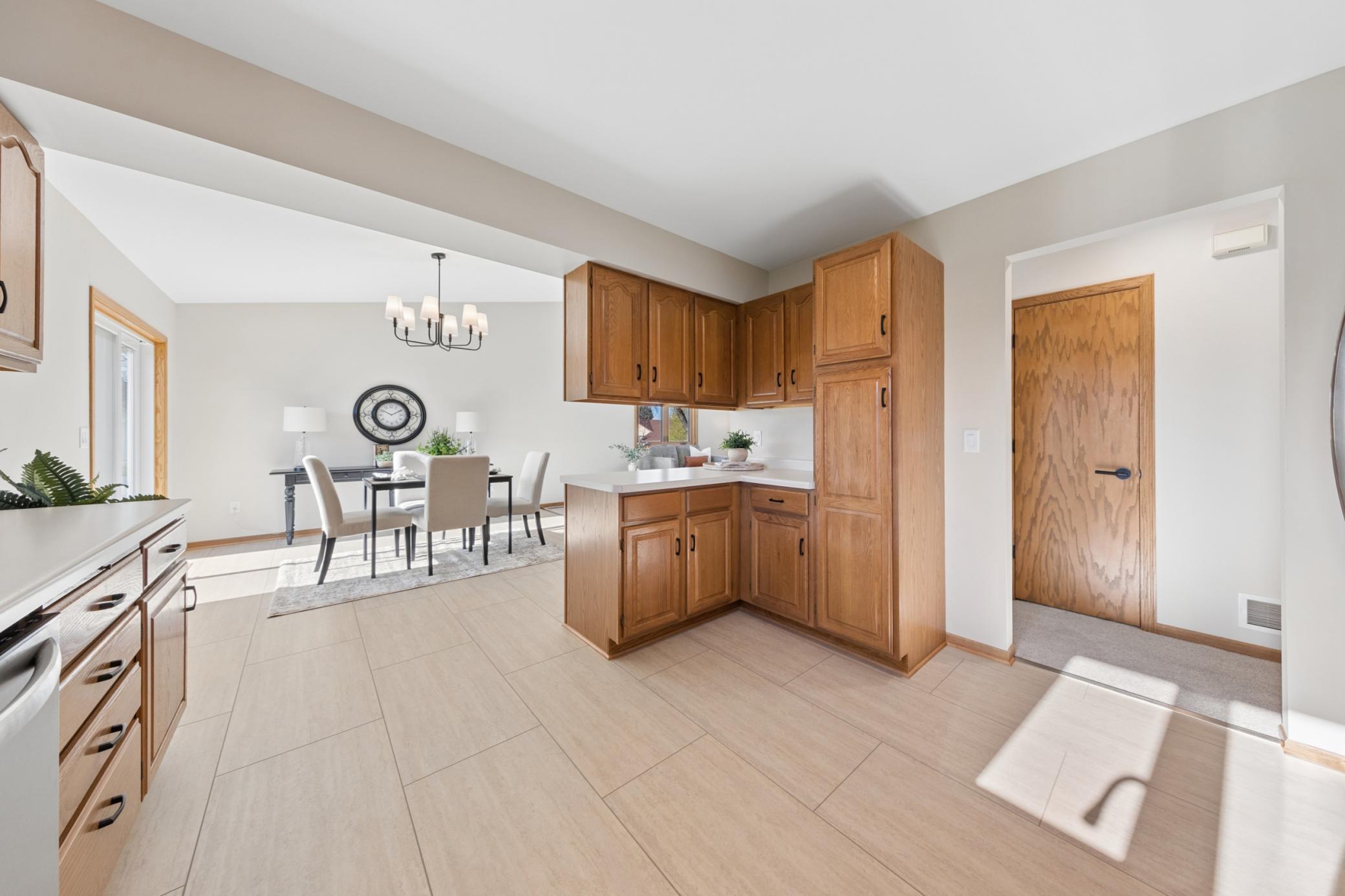 Thoughtfully updated kitchen featuring new LVP flooring, ample oak cabinetry, and modern hardware, seamlessly connected to the dining space.