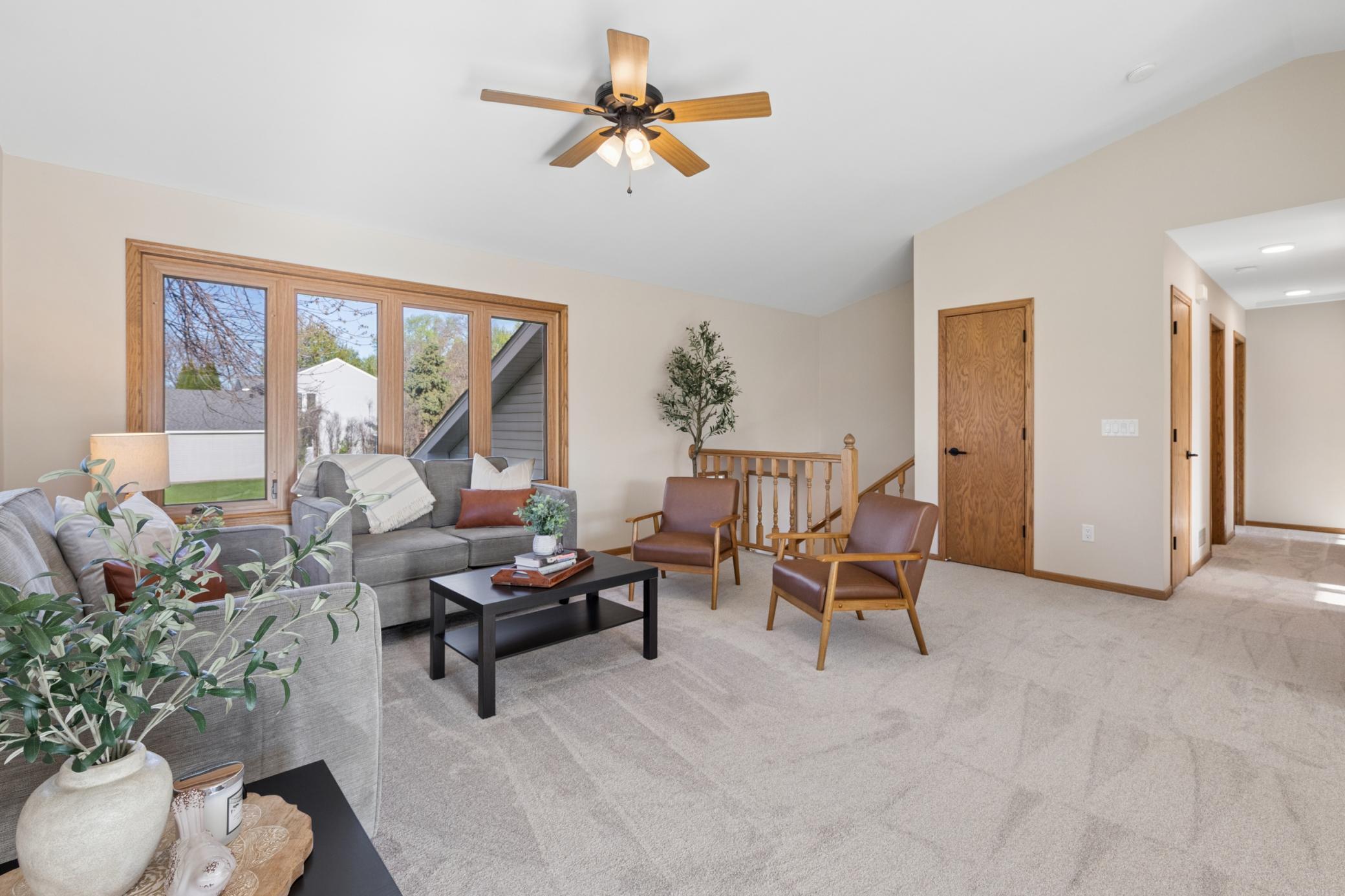 Expansive living room with vaulted, newly scraped, and freshly painted ceilings, bathed in natural light. Also featuring brand-new carpeting and updated lighting throughout.