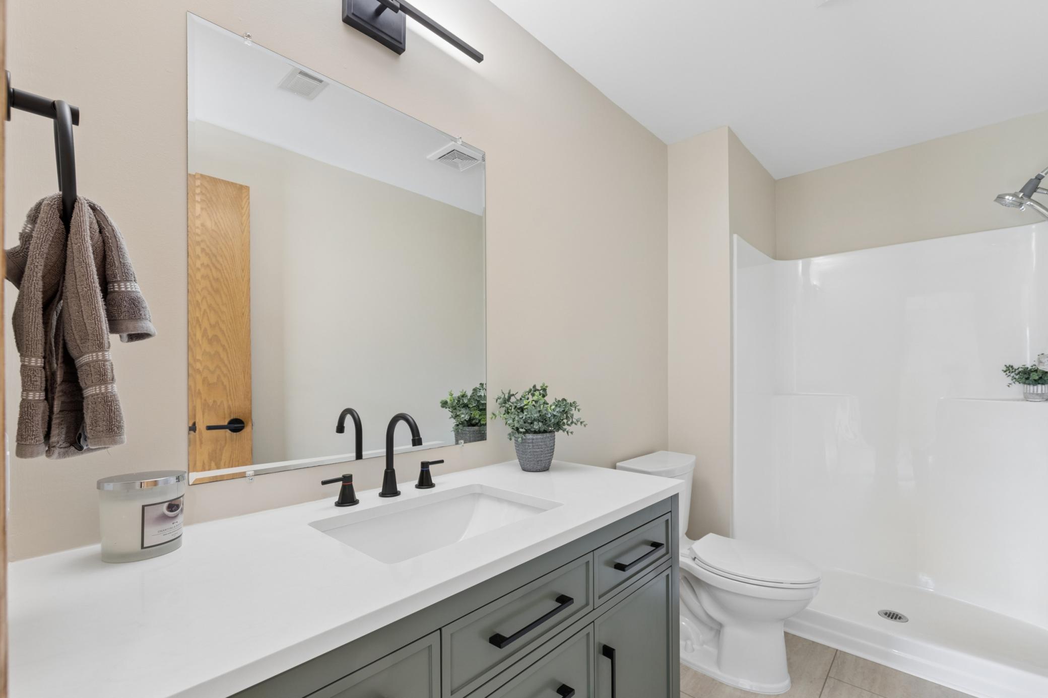 Fully refreshed lower-level bathroom featuring a modern new vanity, updated lighting, durable LVP flooring, and a new toilet.