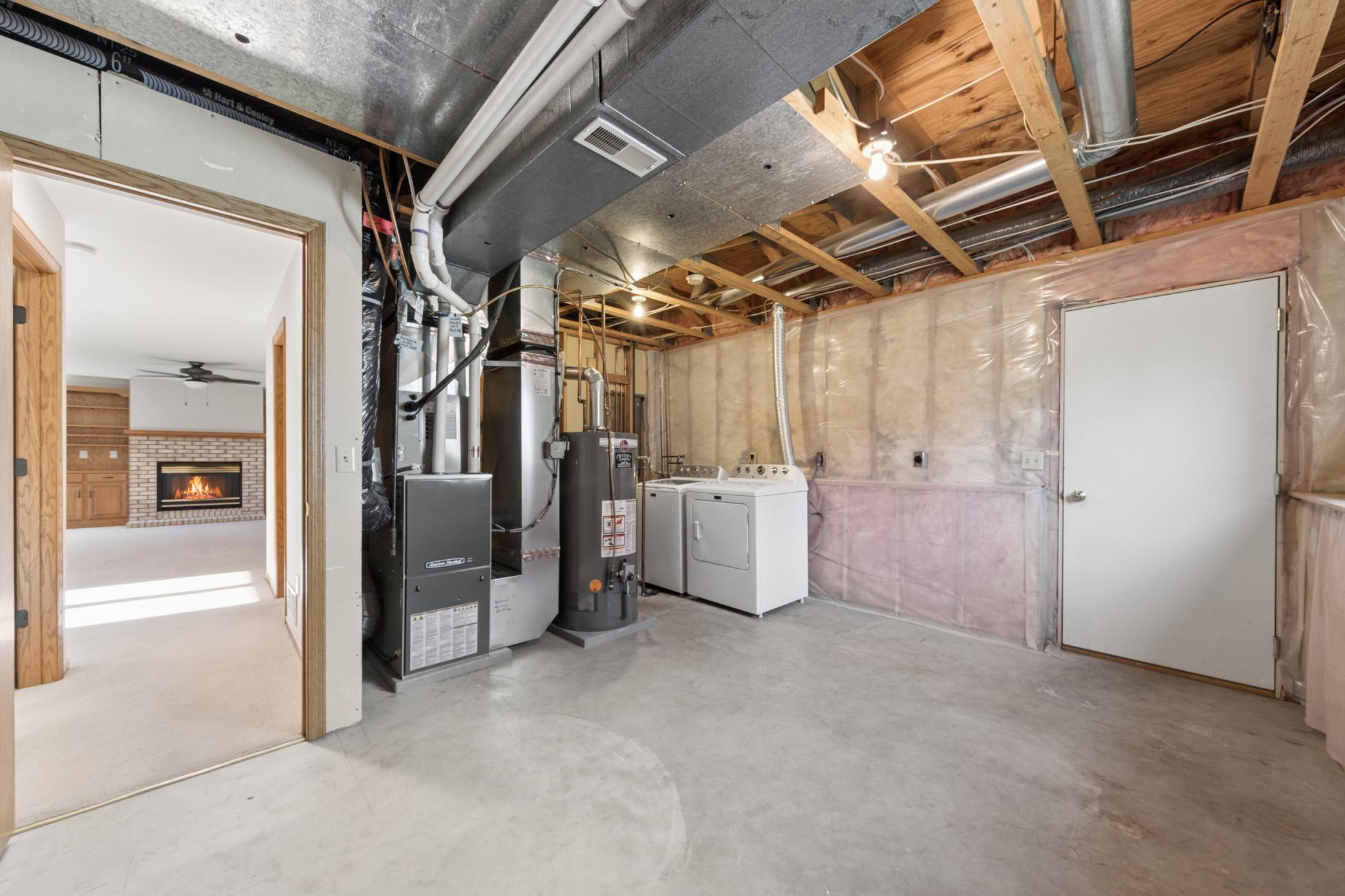 Clean, organized utility room equipped with a new washer and dryer set. Great functional storage and utility area with convenient, direct access to the 3-car garage.