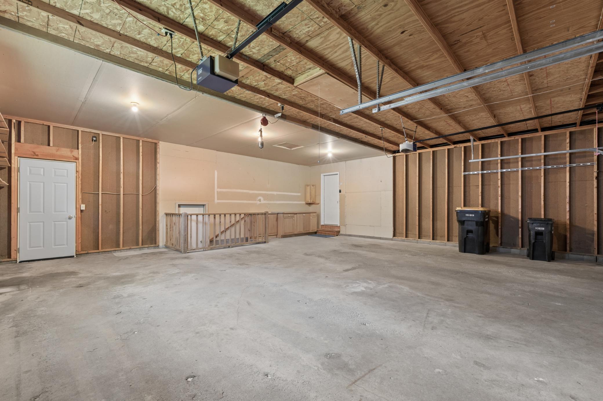 Immaculate, oversized 3-car garage space, meticulously maintained and organized for pristine storage and vehicle parking. Access to front entrance or stairs to lower level utility room.