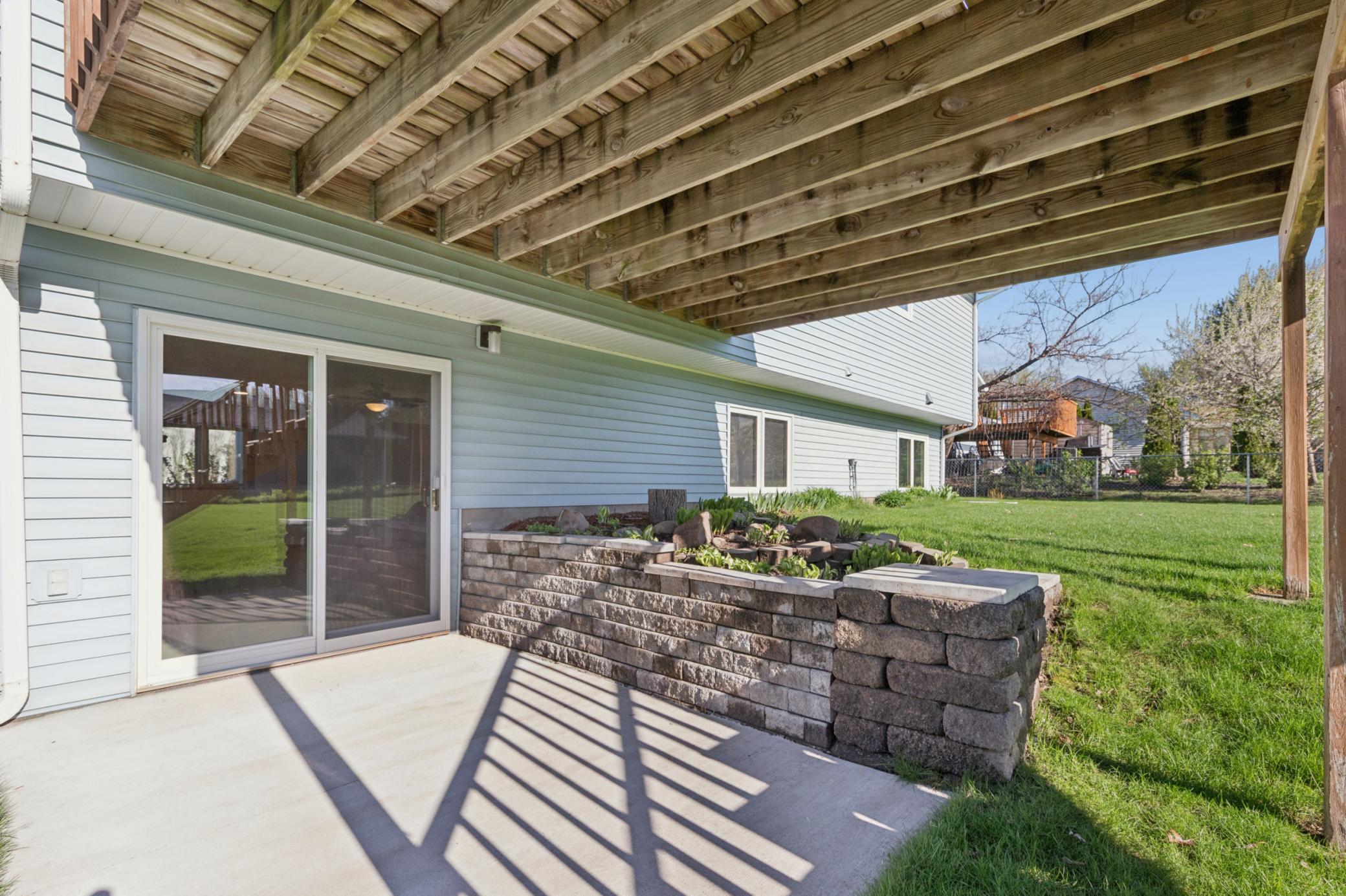 Walkout access from the lower level leading to the backyard, complemented by a newer, professionally installed retaining wall.