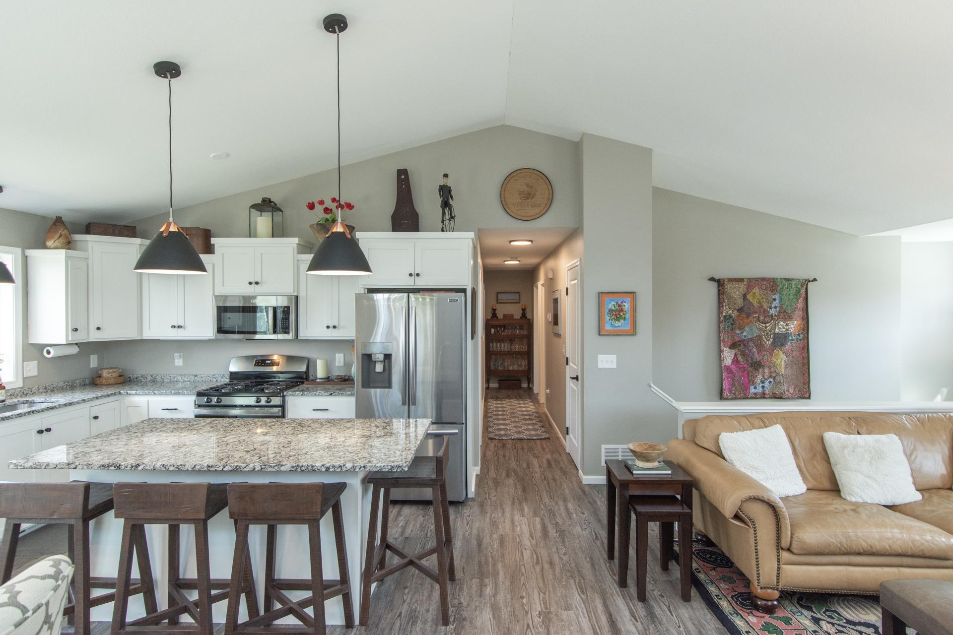 Open-concept kitchen with granite countertops, stainless steel appliances, custom cabinetry, and a large center island with seating.