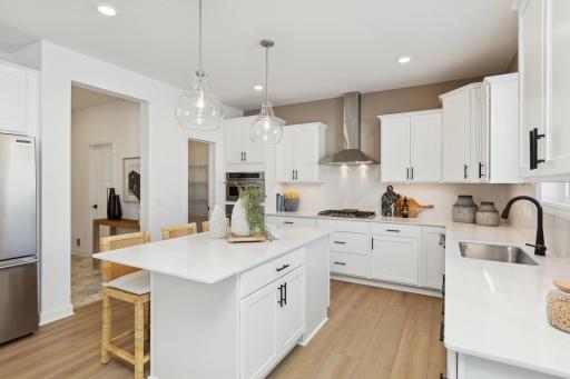 (Photo of decorated model, actual homes finishes will vary) The stunning gourmet kitchen features a large center island, quartz countertops, LVP floors, stainless appliances and more!