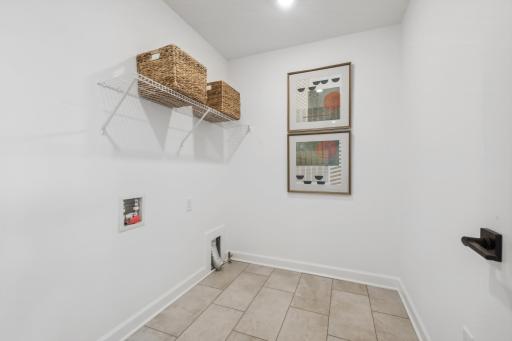(Photo of decorated model, actual homes finishes will vary) Upper level laundry room is set up for a gas dryer.