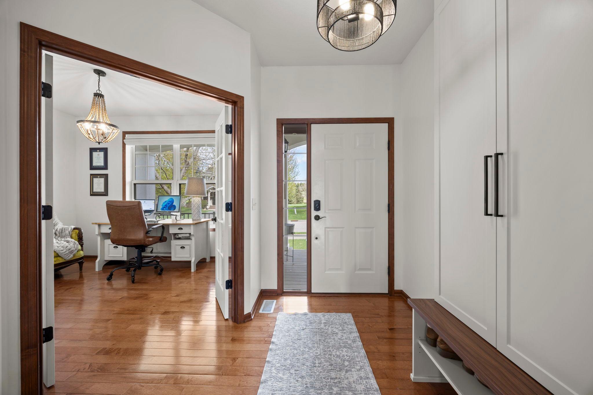 The inviting foyer features built-in cabinets and shoe storage, along with warm wood flooring that extends throughout the main level.