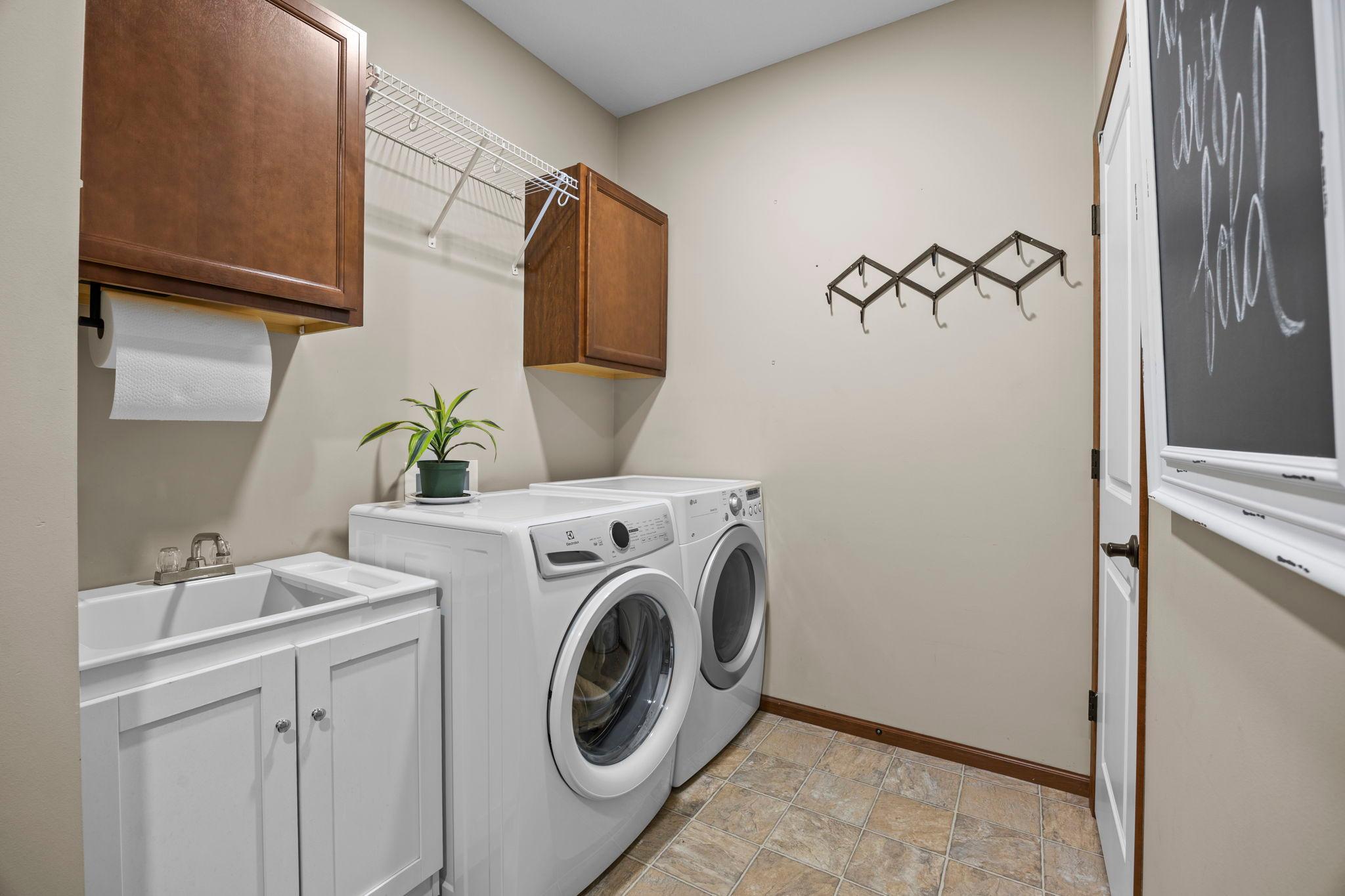 Completing the main level is a laundry room with a front-loading washer and dryer, sink, cabinetry, and closet storage, along with direct access to the insulated and heated attached three-car garage.