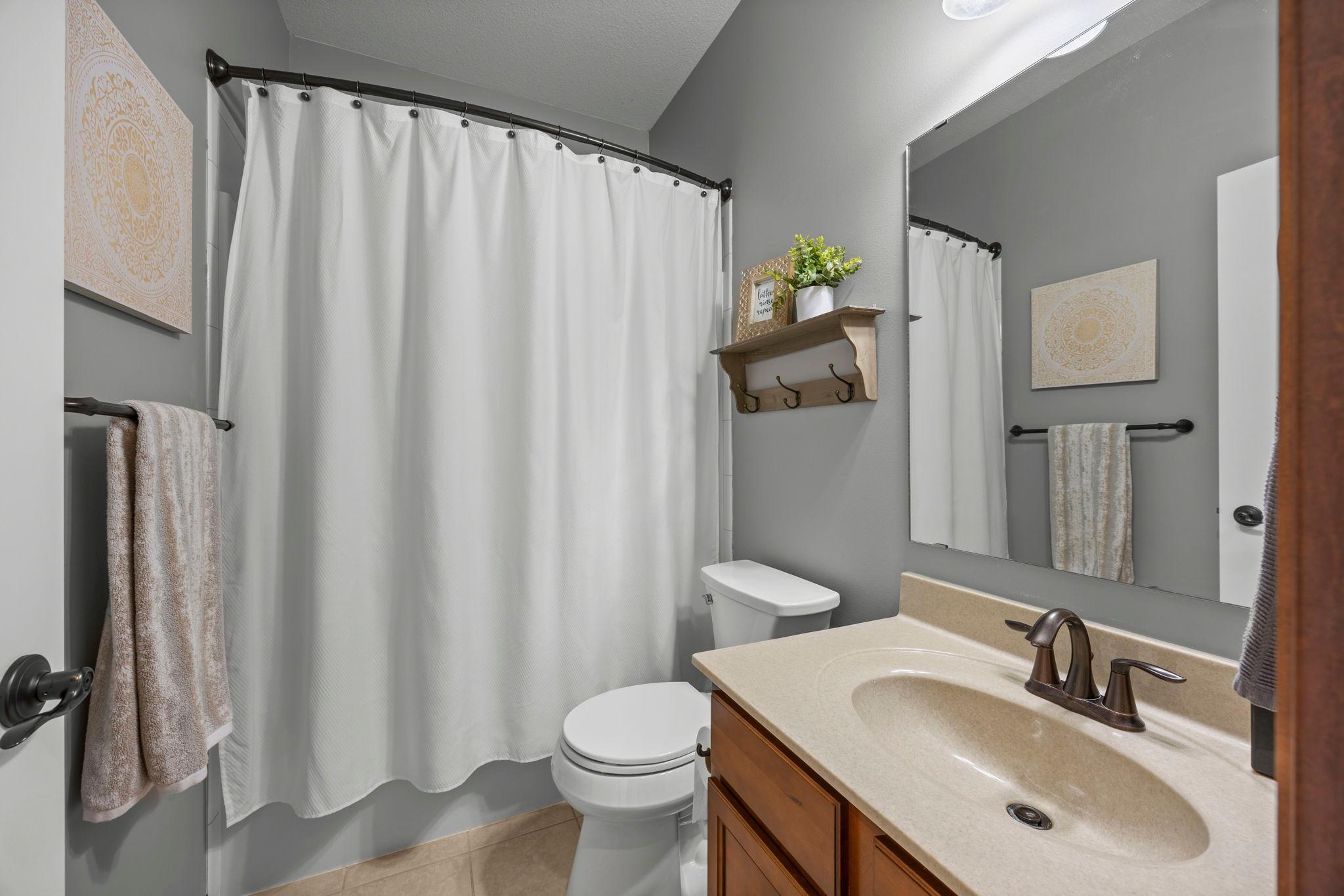 Just steps away is an additional full bathroom featuring a tub and shower combination with a single vanity.