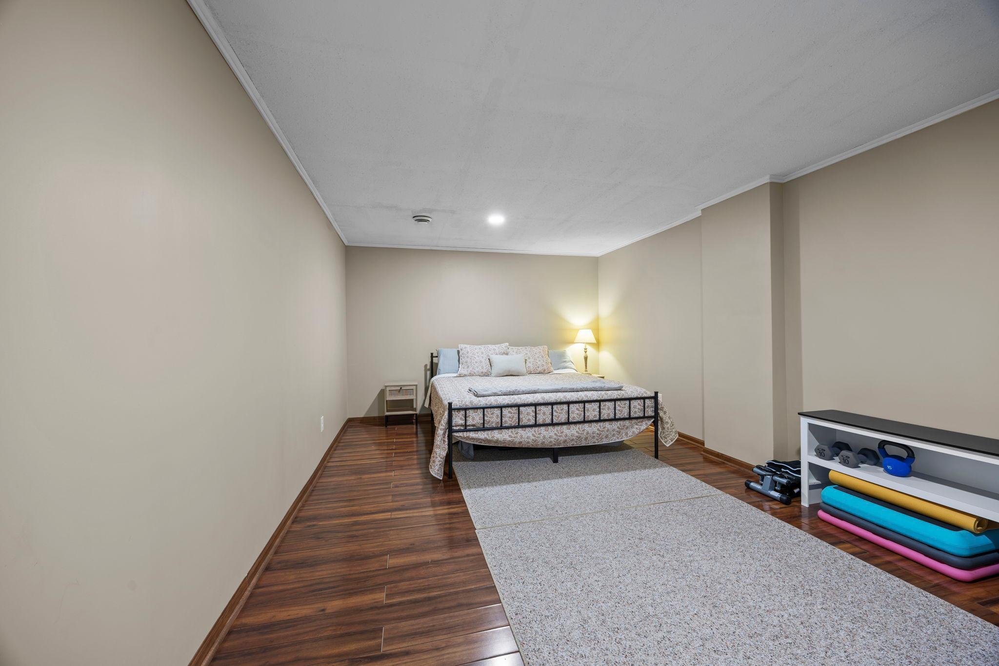 Adjacent to the family room is a large recreation space with wood flooring—perfect for a home gym, playroom, or easily converted into a fifth bedroom.