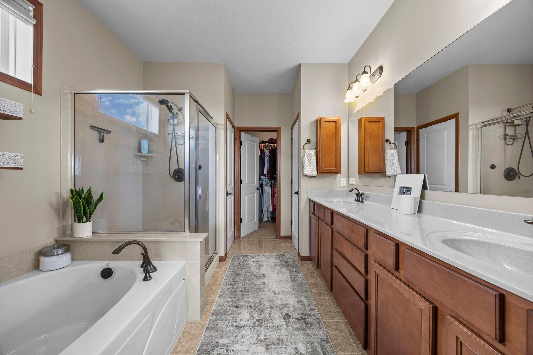 The private ensuite offers a spa-like soaking tub, walk-in shower, dual vanities with generous storage, a separate water closet, and a 9x6 walk-in closet.