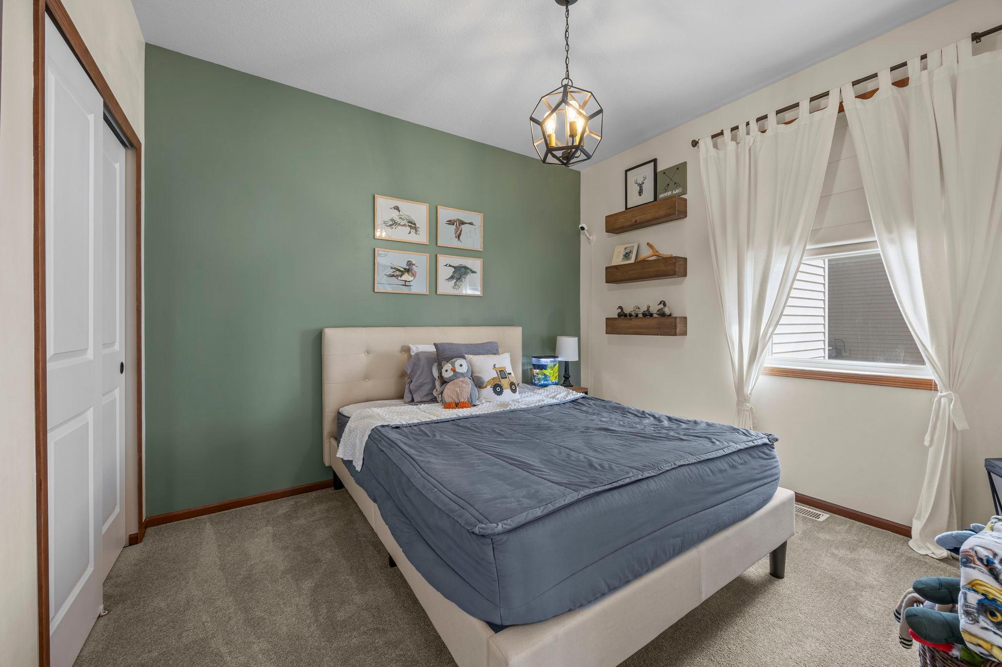 The third bedroom offers carpeting, a distinctive light fixture, and ample closet space.
