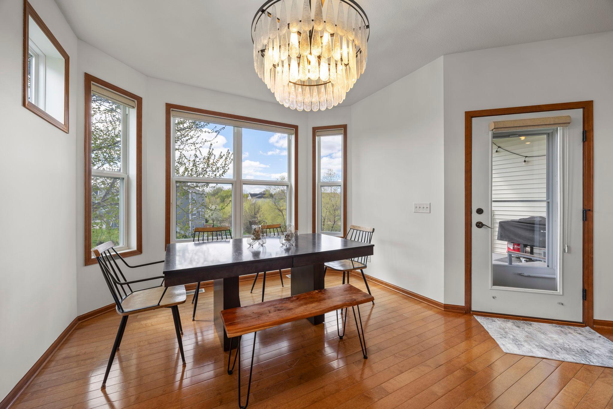 The kitchen flows seamlessly into the dining area, where a statement chandelier and large windows fill the space with natural light and provide access to a covered, maintenance-free deck.