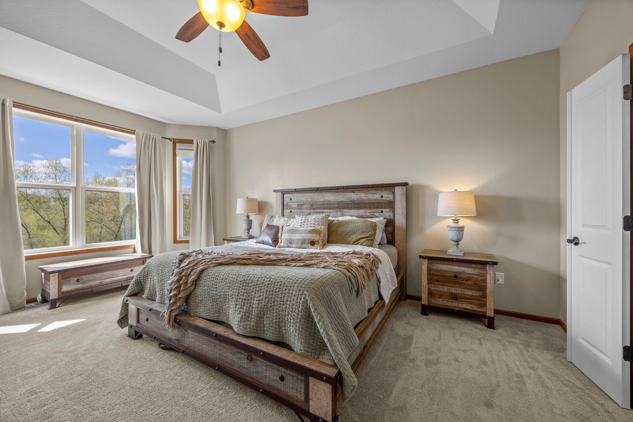 The main level also includes three bedrooms, highlighted by a spacious primary suite with carpeting, a large bay window, tray ceilings, and a ceiling fan.