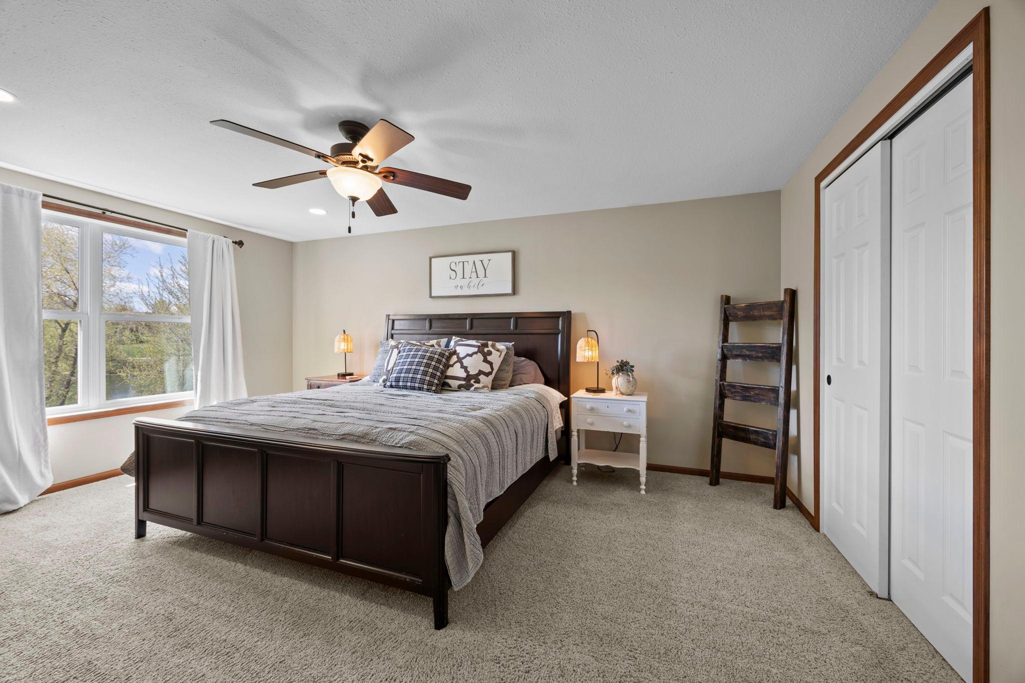 The fourth bedroom features carpeting, a ceiling fan, a large window, and ample closet space.