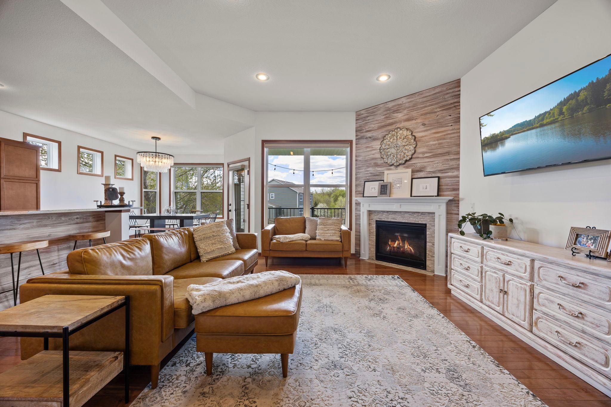 The main-level living room is designed for comfort, featuring a cozy gas fireplace, recessed lighting, and a large window that creates a bright and relaxing atmosphere.