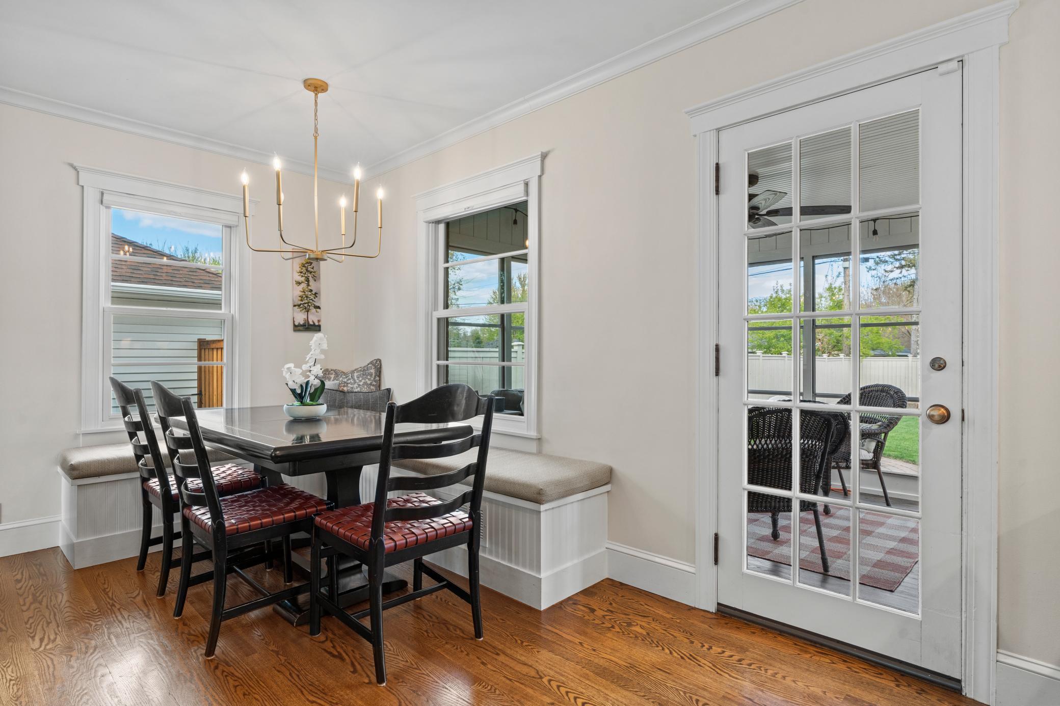 Adjacent to the kitchen is a charming dining area with built-in bench seating and a classic chandelier, offering access to the glass-enclosed three-season porch.