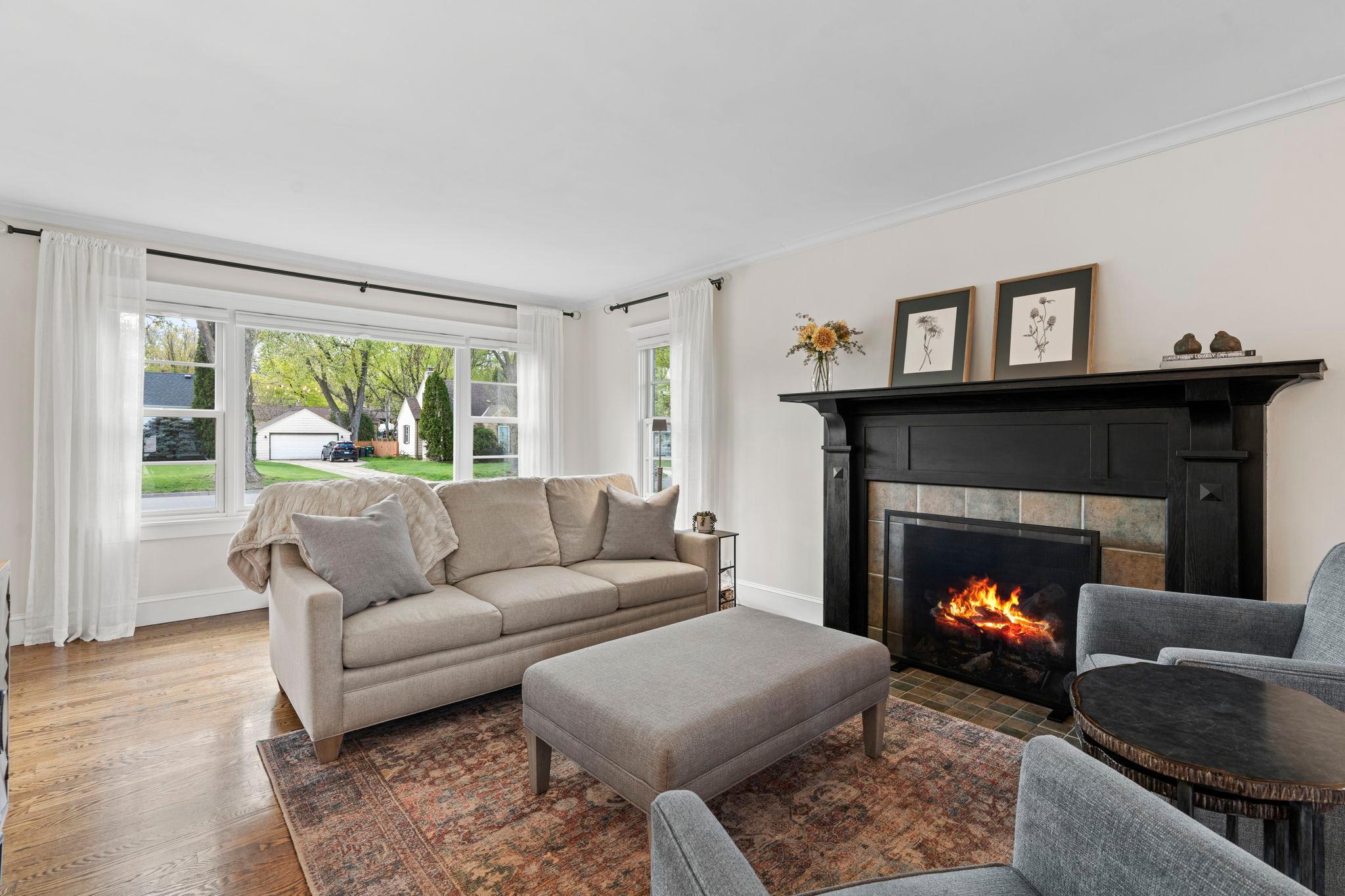 The main-level living room is bright and welcoming, highlighted by large front-facing windows, a cozy gas fireplace, and an elegant mantel.